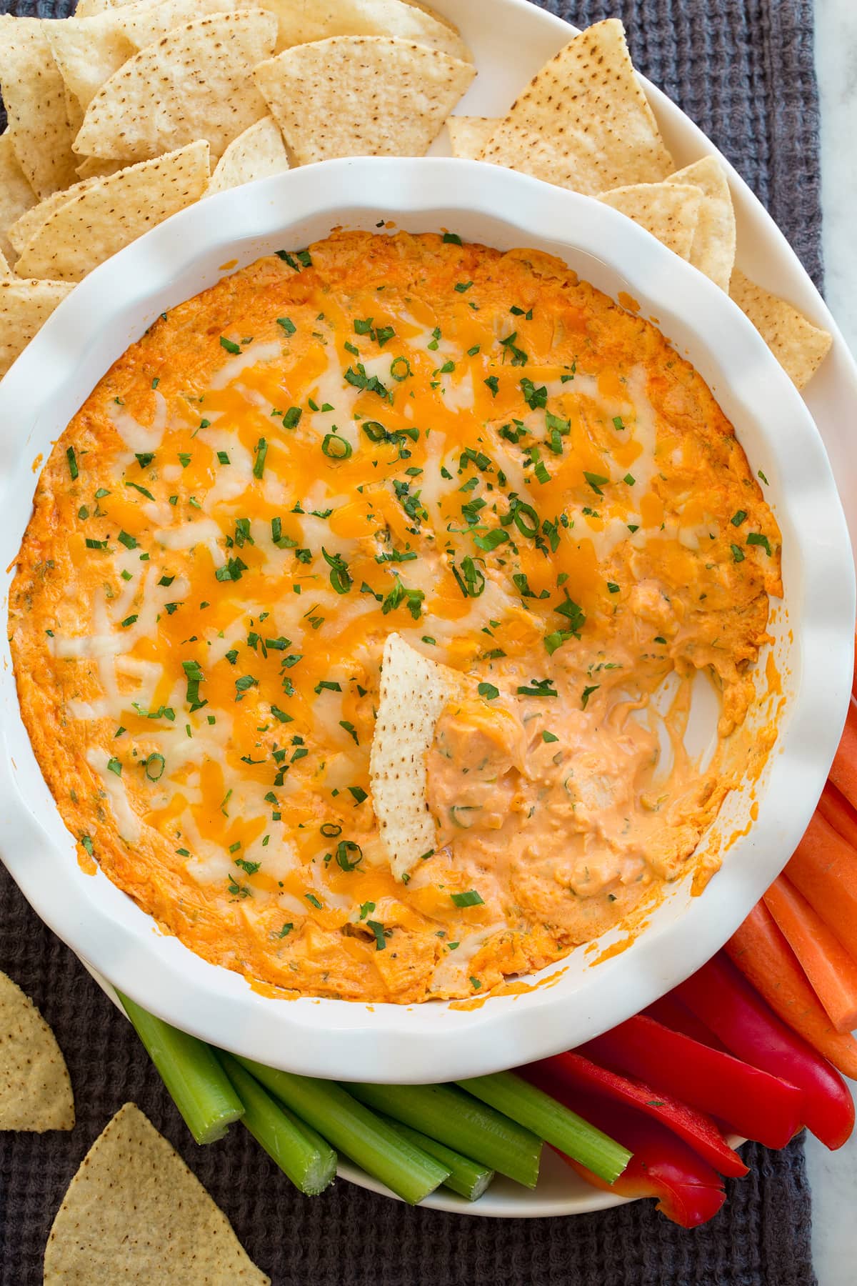 Buffalo Chicken Dip Overhead photo of buffalo chicken dip shown with serving suggestions on the side of carrots, bell pepper, celery and tortilla chips.