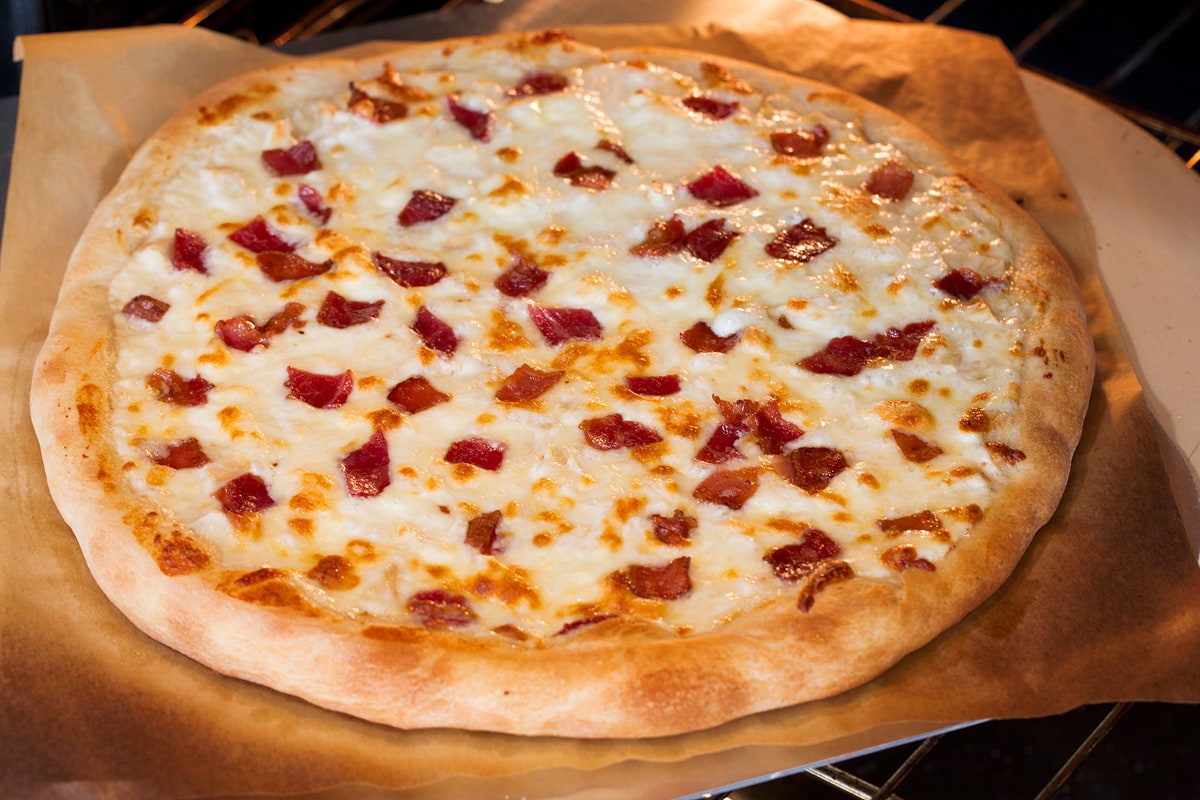 Photo of alfredo pizza being baked in the oven.