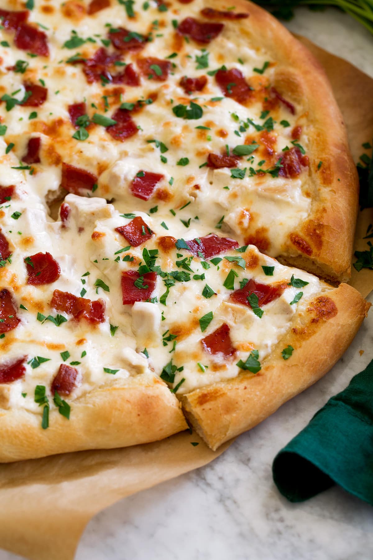 Side angle of sliced chicken alfredo pizza.