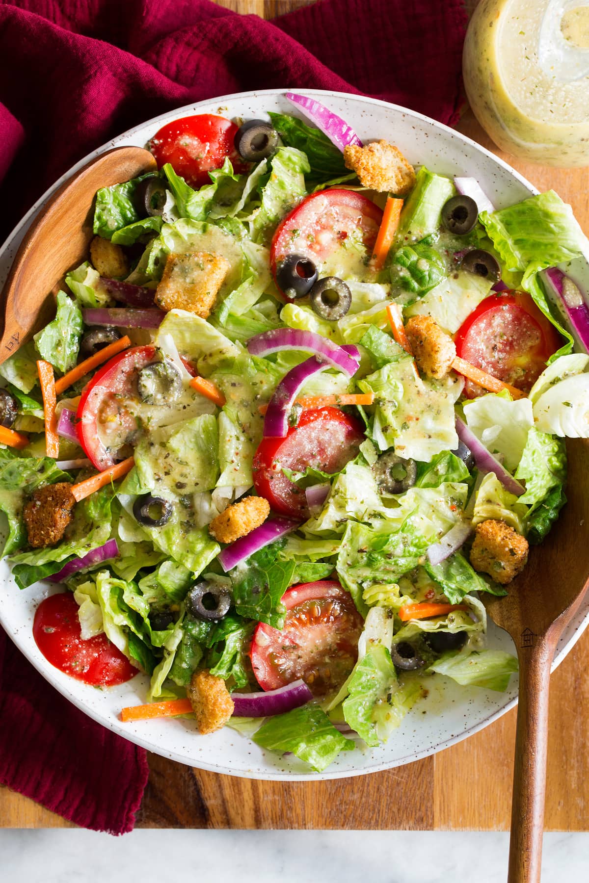 Photo: Green iceberg and romaine salad with carrots, olives and tomatoes that has been topped with Italian salad dressing.