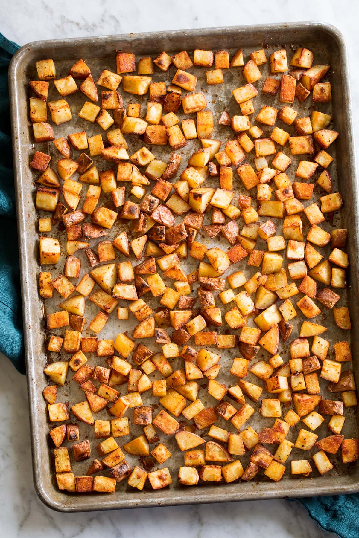 Breakfast Potatoes Photo: Crispy browned breakfast potatoes on a sheet pan set on a white marble surface.