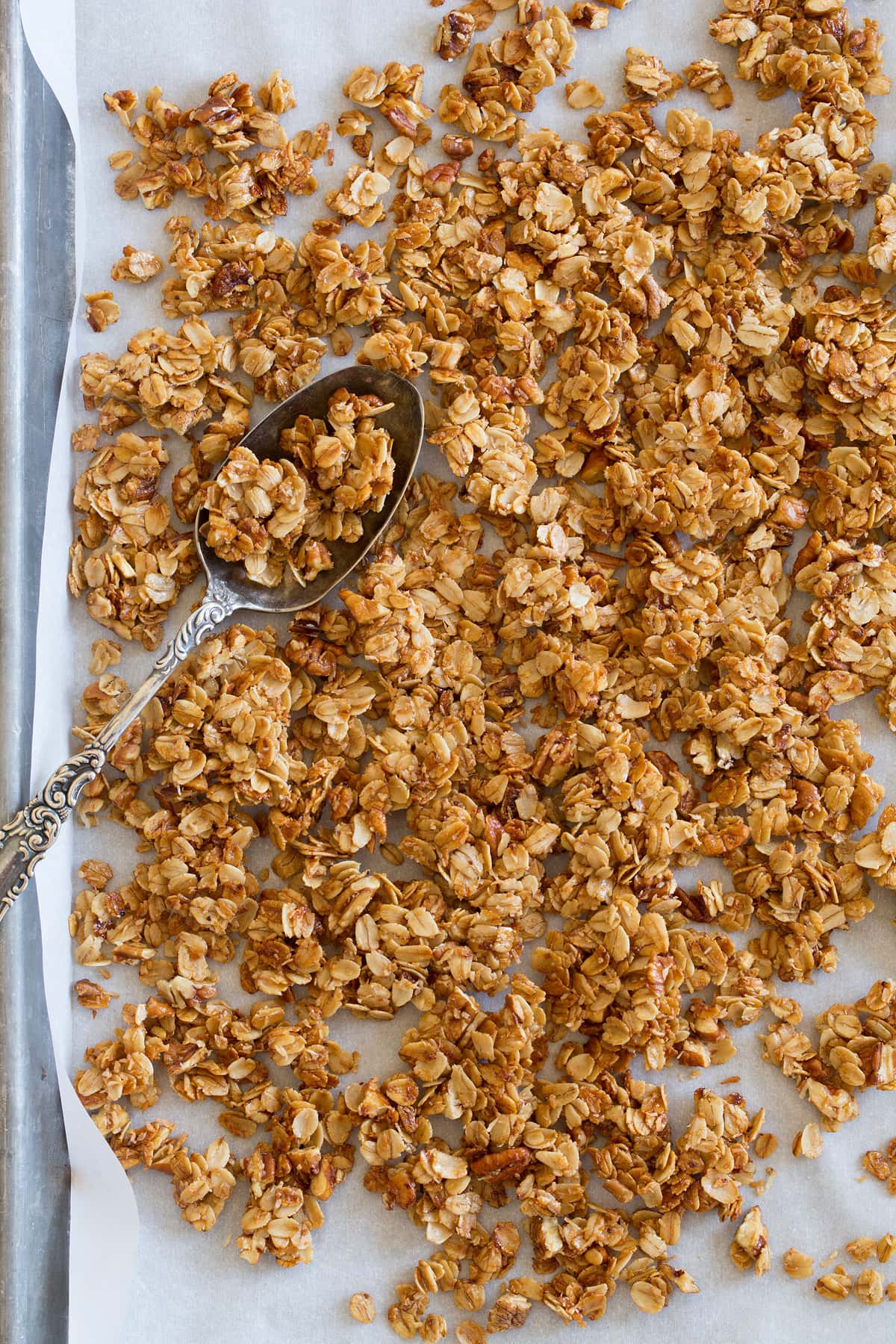 Easy Stovetop Granola Recipe Homemade granola recipe shown spread out on a baking sheet with parchment paper.