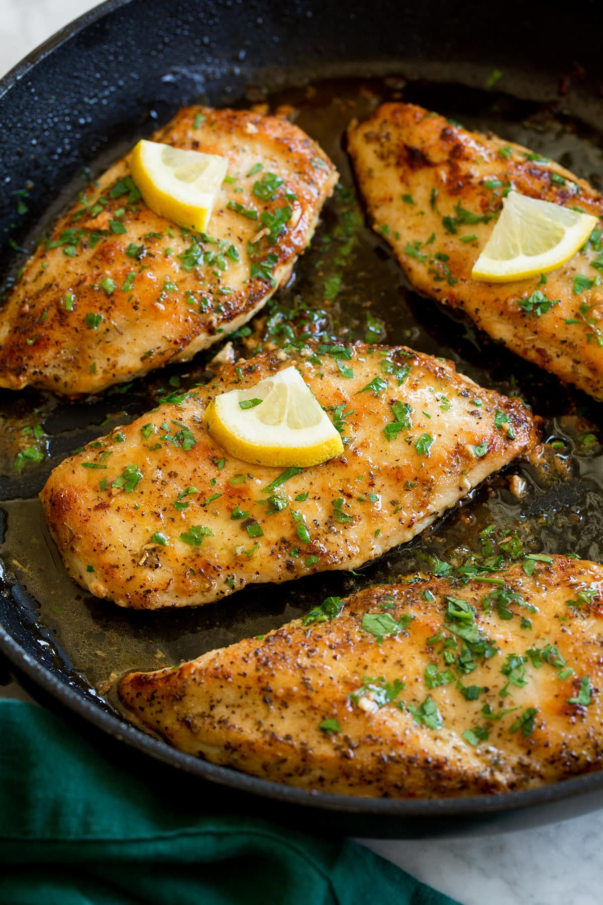 Lemon pepper chicken breasts in a black skillet.