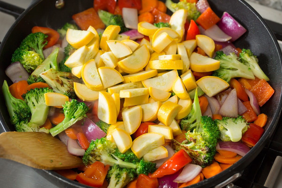 Photo: Adding squash to vegetable mixture in skillet.