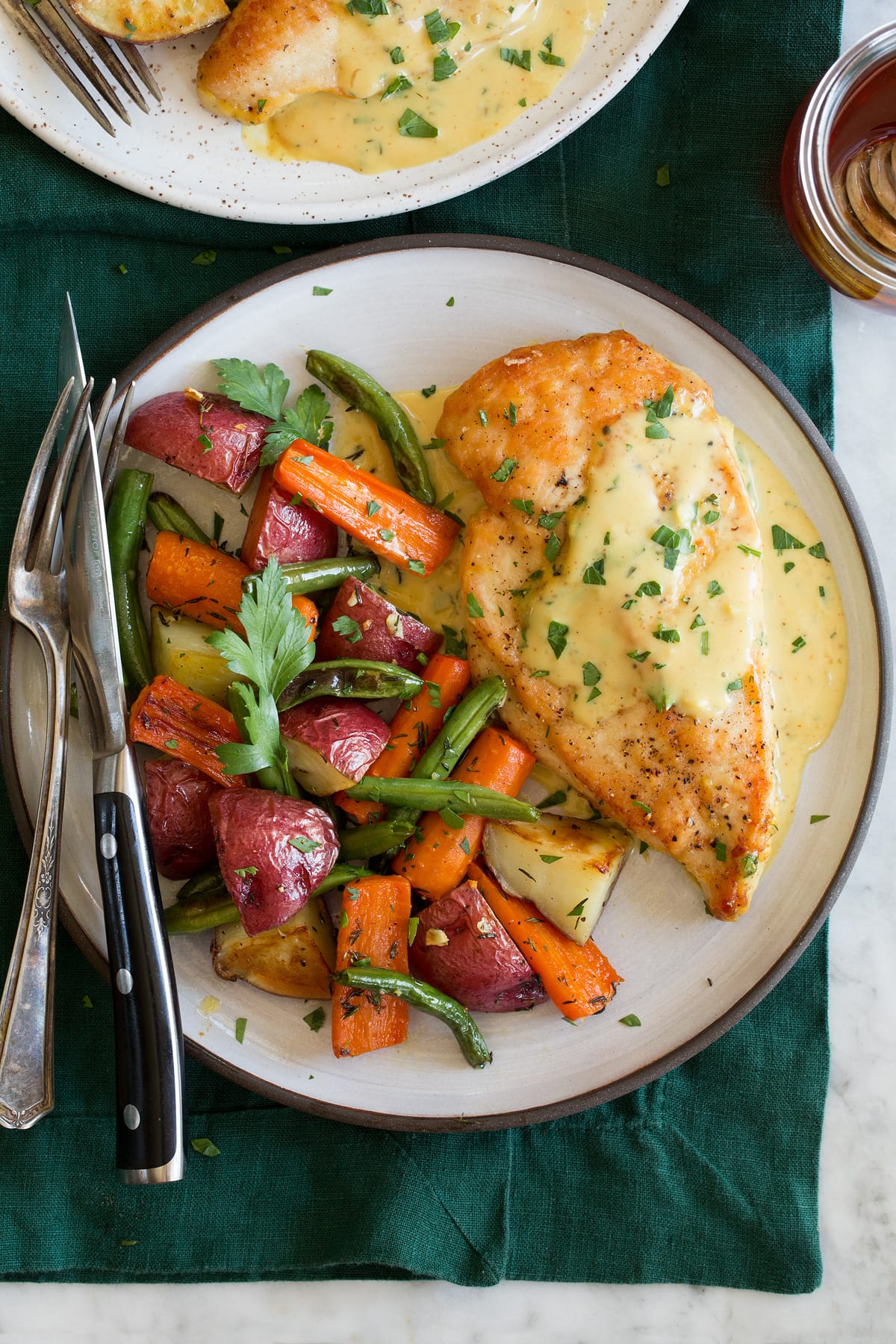 Honey mustard chicken shown with a serving suggestion of roasted vegetables on a serving plate.