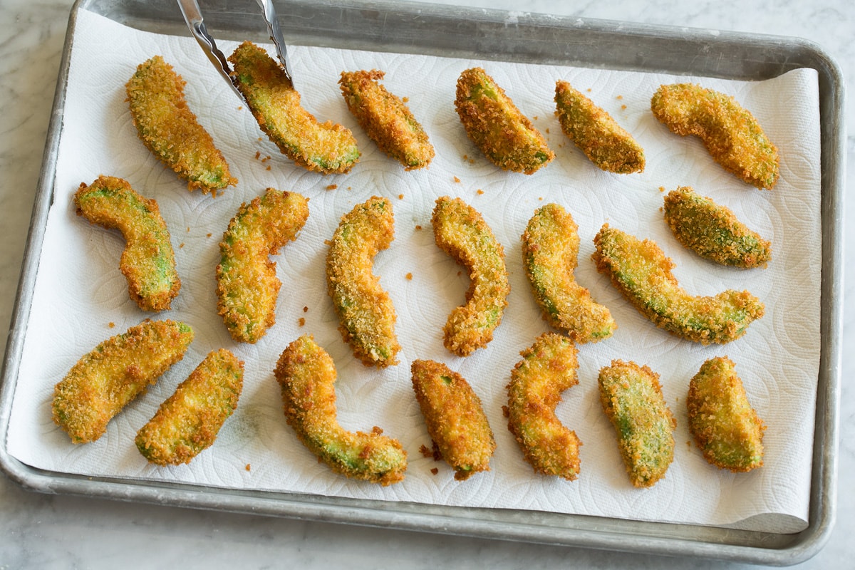 Avocado Fries Avocado fries draining on paper towel lined baking sheet.
