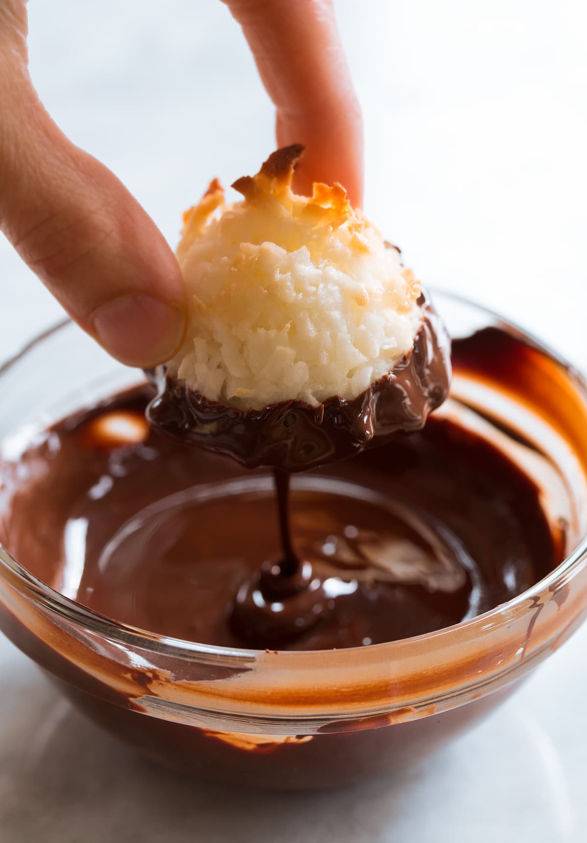 Coconut Macaroon being dipped in chocolate.