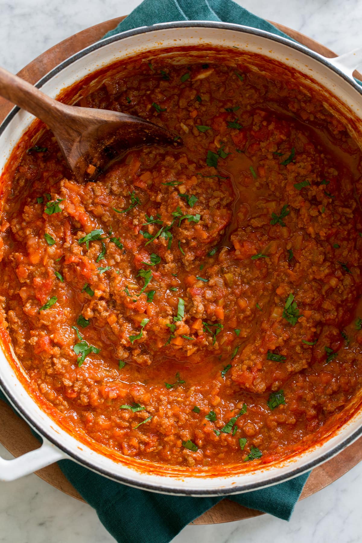 White enameled cast iron pot with bolognese sauce shown from overhead.