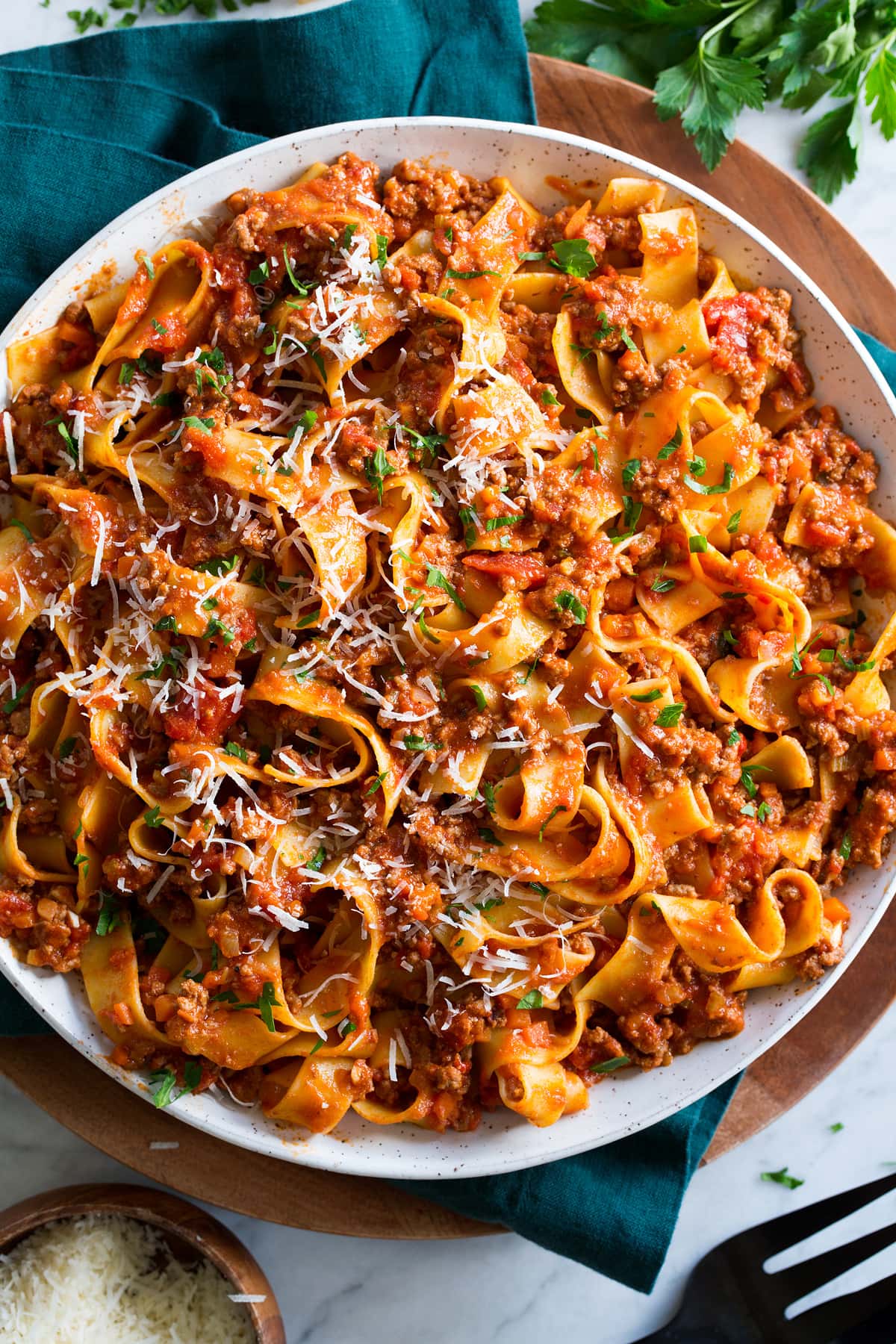 Pappardelle with bolognese sauce, parmesan and parsley garnish.