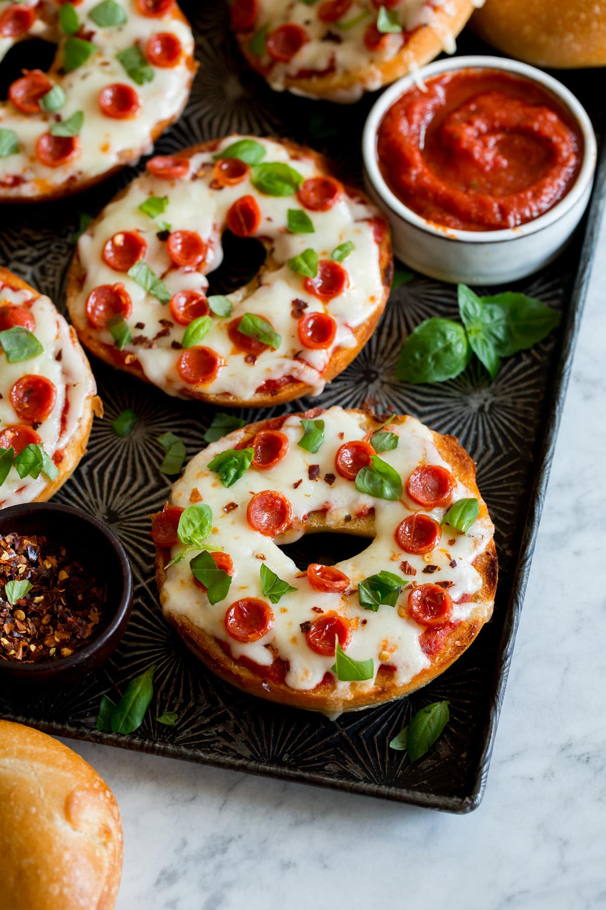 Pizza Bagels Pizza bagels shown close up with mozzarella cheese, pepperoni and basil over top.