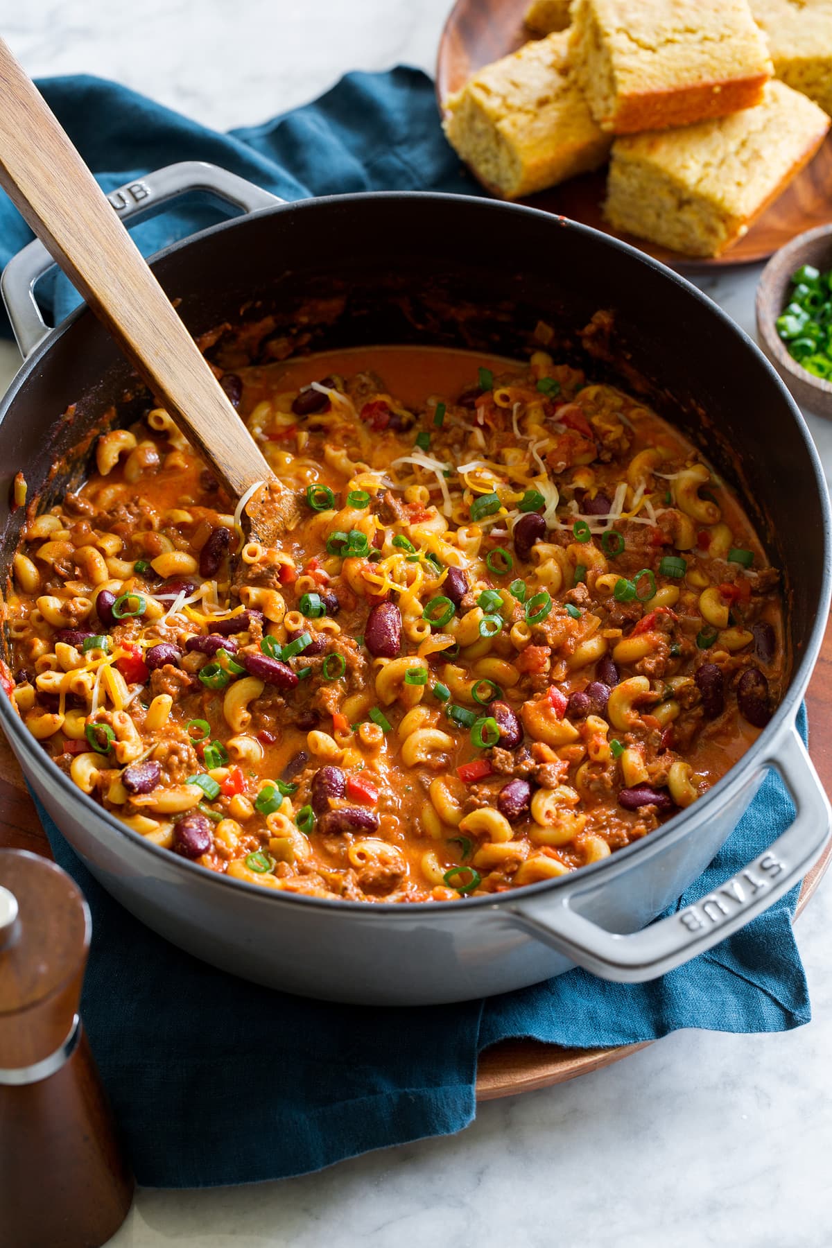 Chili Mac Chili mac in a large pot with a wooden spoon scooping mixture.