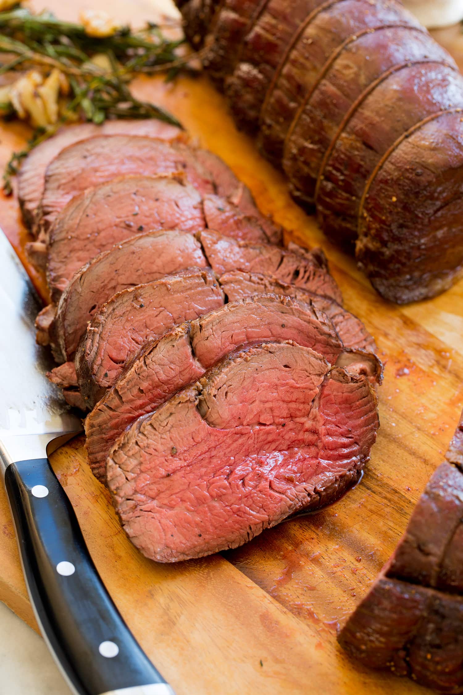 Beef Tenderloin Beef tenderloin sliced on wood cutting board.