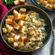 Chicken pot pie mixture in a blue bowl topped with puff pastry bites.