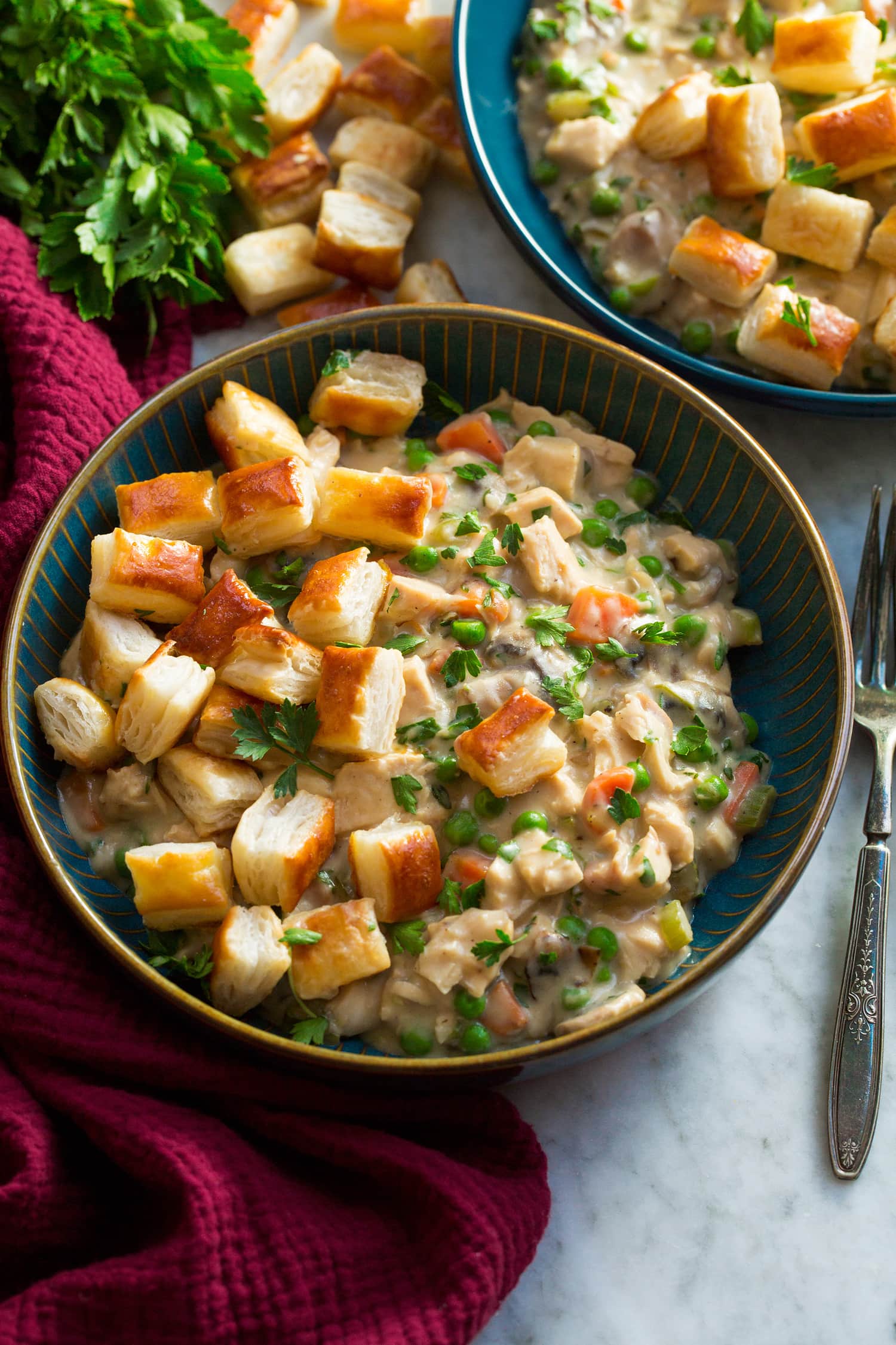 Chicken pot pie mixture in a blue bowl topped with puff pastry bites.