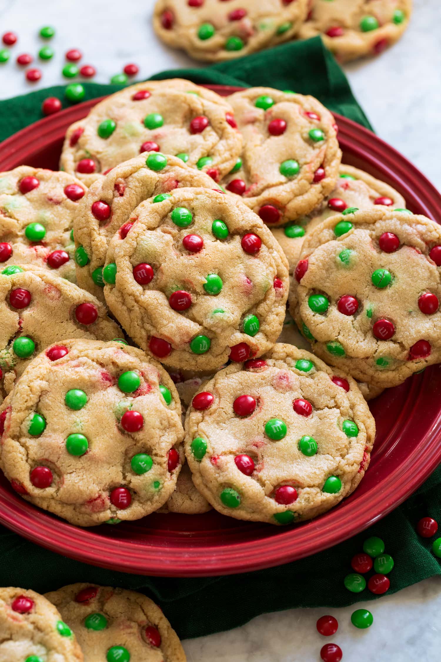 Cookies with mini red and green m&m's shown on a red plate.