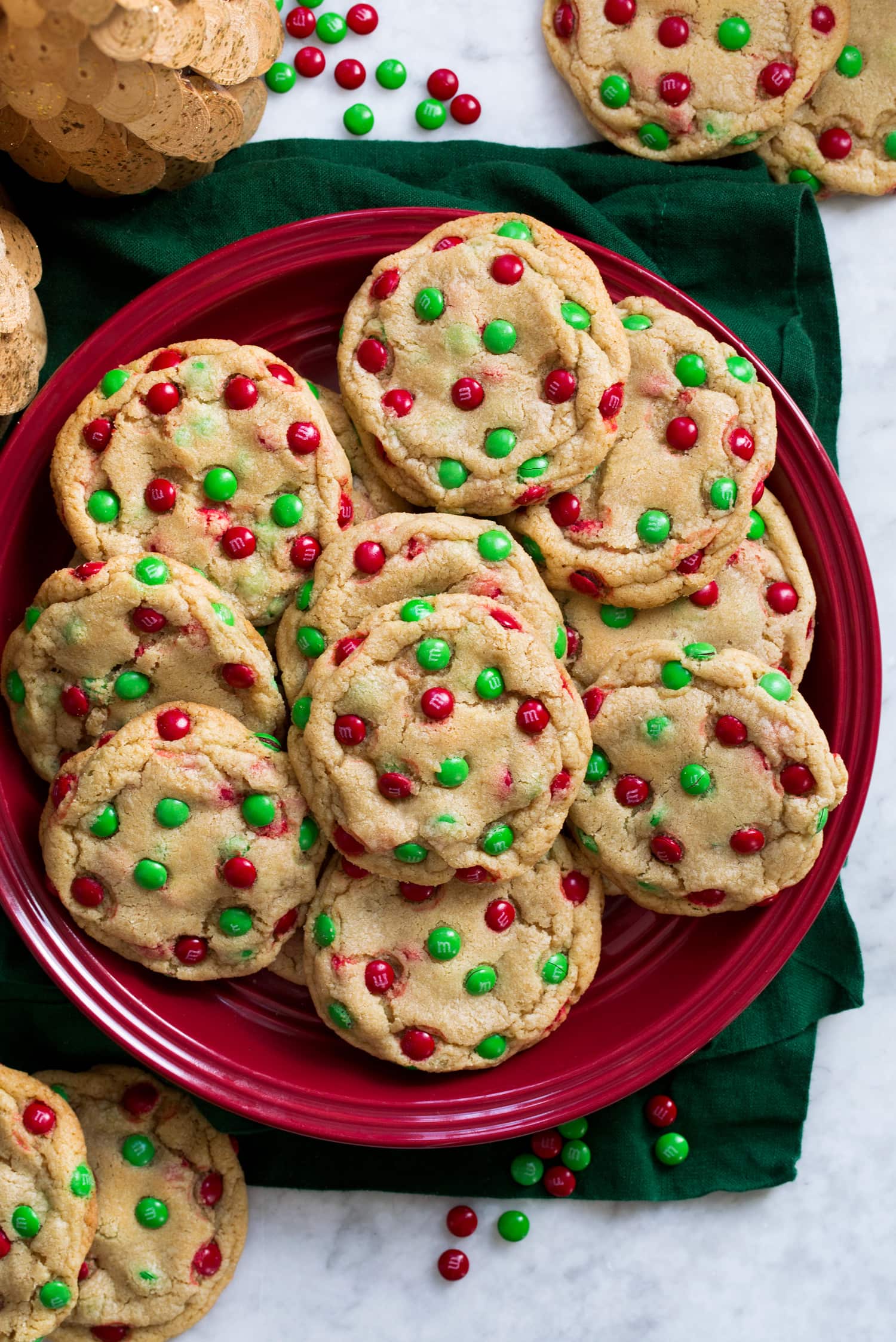 M&M Cookies M and M Christmas cookies on a red plate over a green cloth.