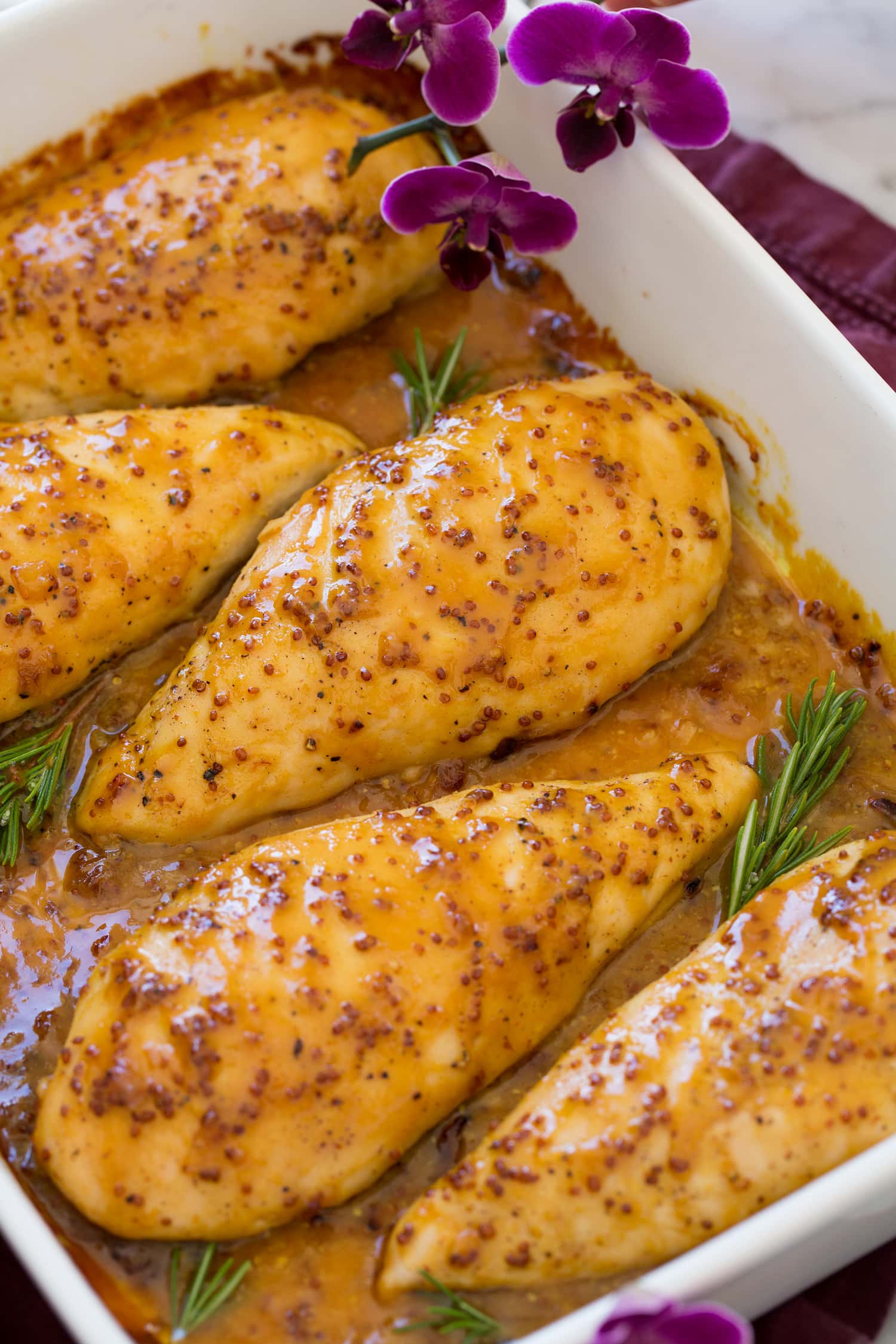 Baked Honey Mustard Chicken Close up photo of honey mustard chicken breast in baking dish.