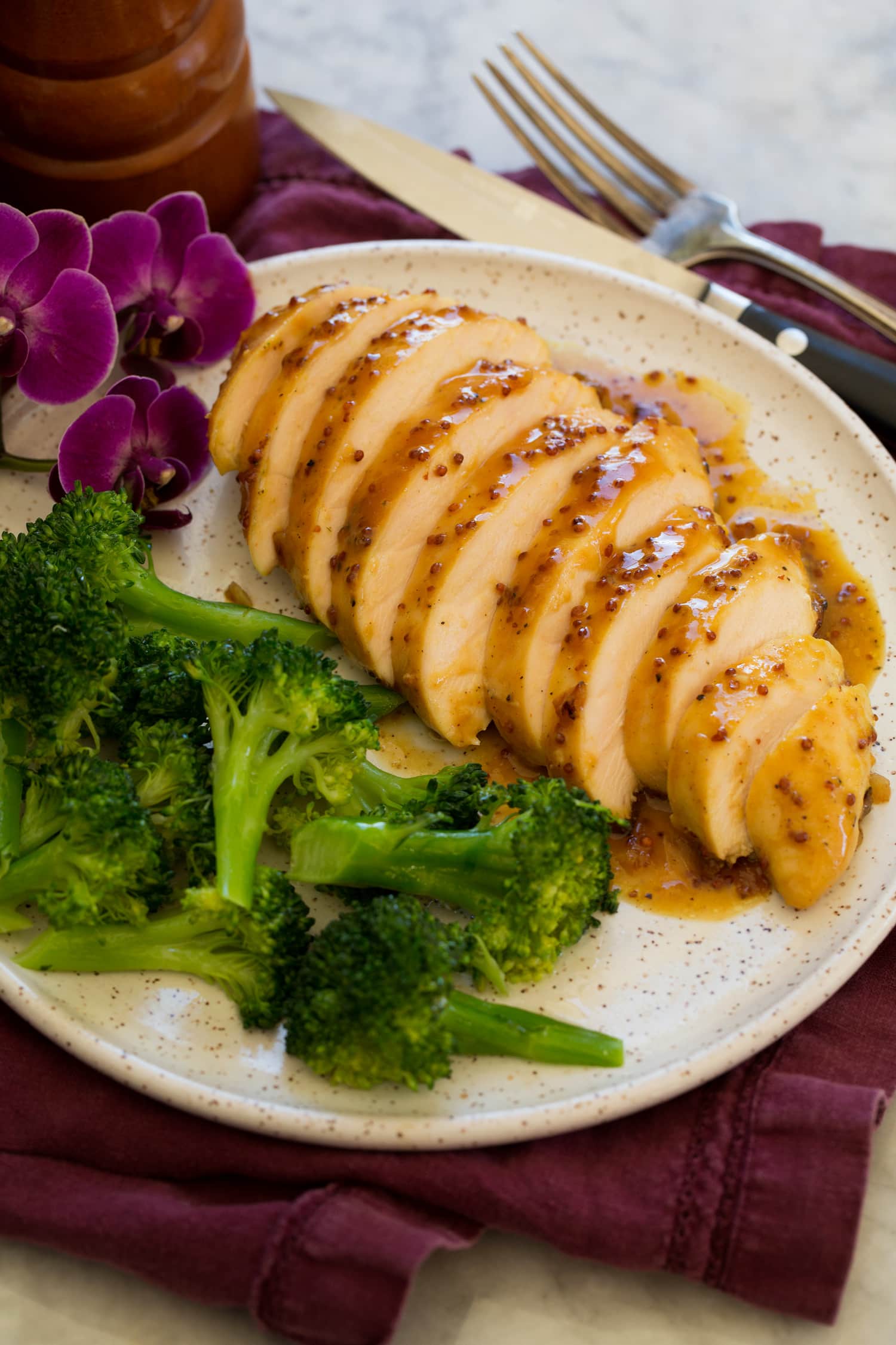 Baked Honey Mustard Chicken Sliced chicken with honey mustard on a plate with steamed broccoli as a serving suggestion.
