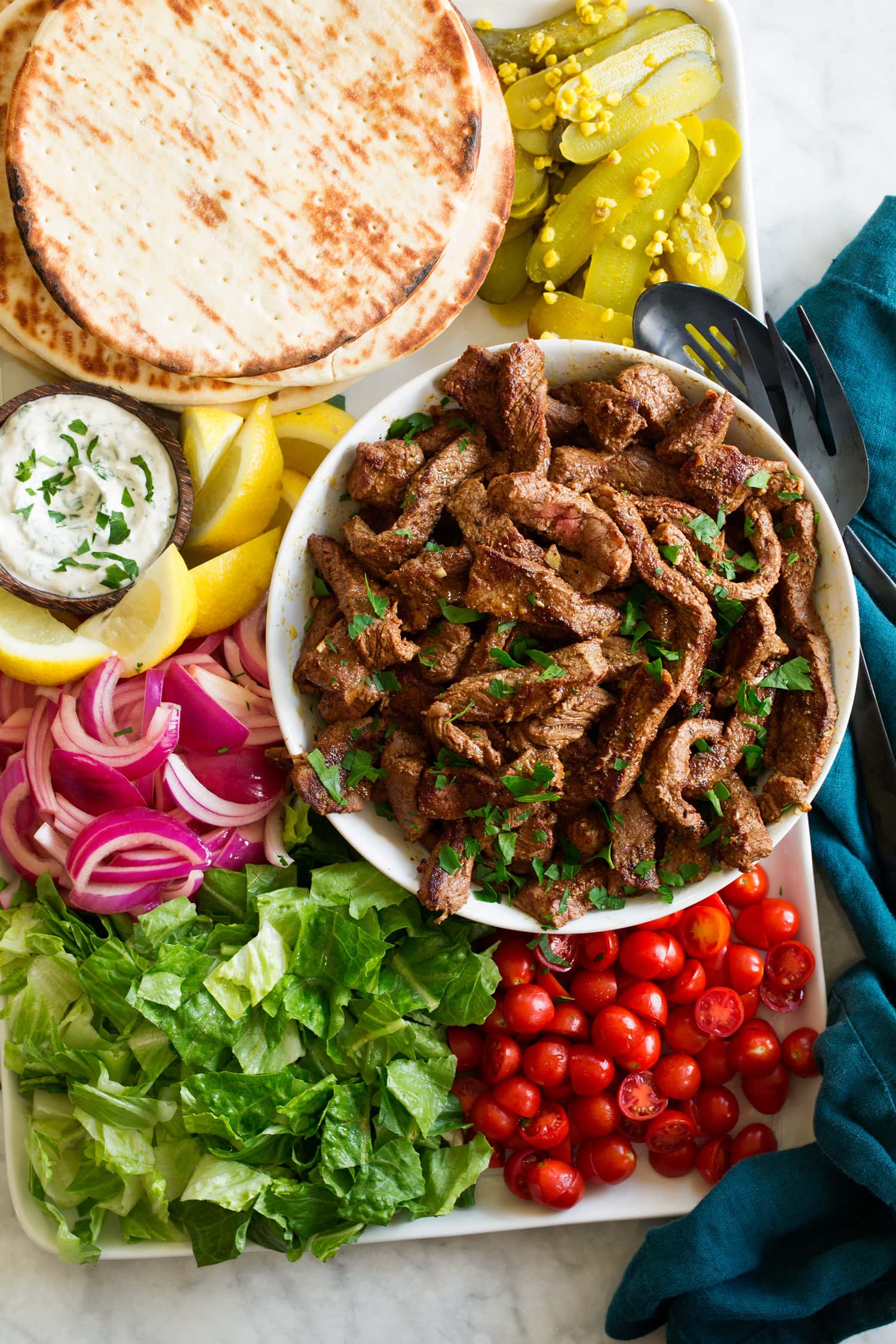 Beef Shawarma Seared beef shawarma strips shown on a platter with serving suggestions.