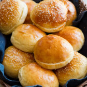 Homemade hamburger buns shown in a basket with a blue cloth.