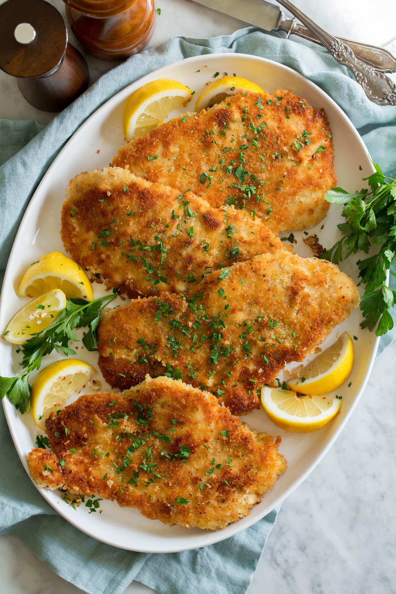 Overhead photo of four servings of breaded fried thin chicken breasts.
