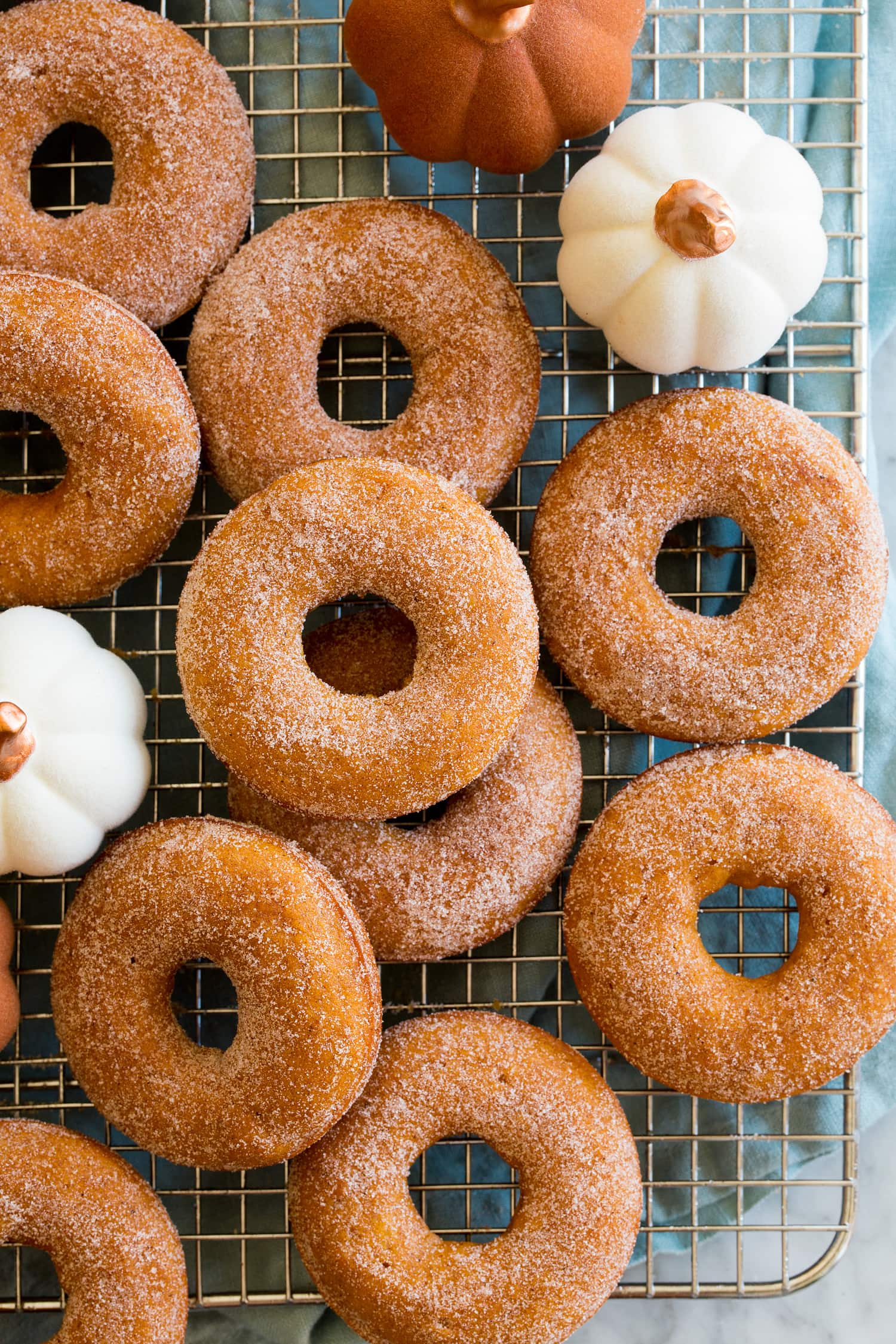 Overheat close up photo of homemade pumpkin donuts on a cooling rack.