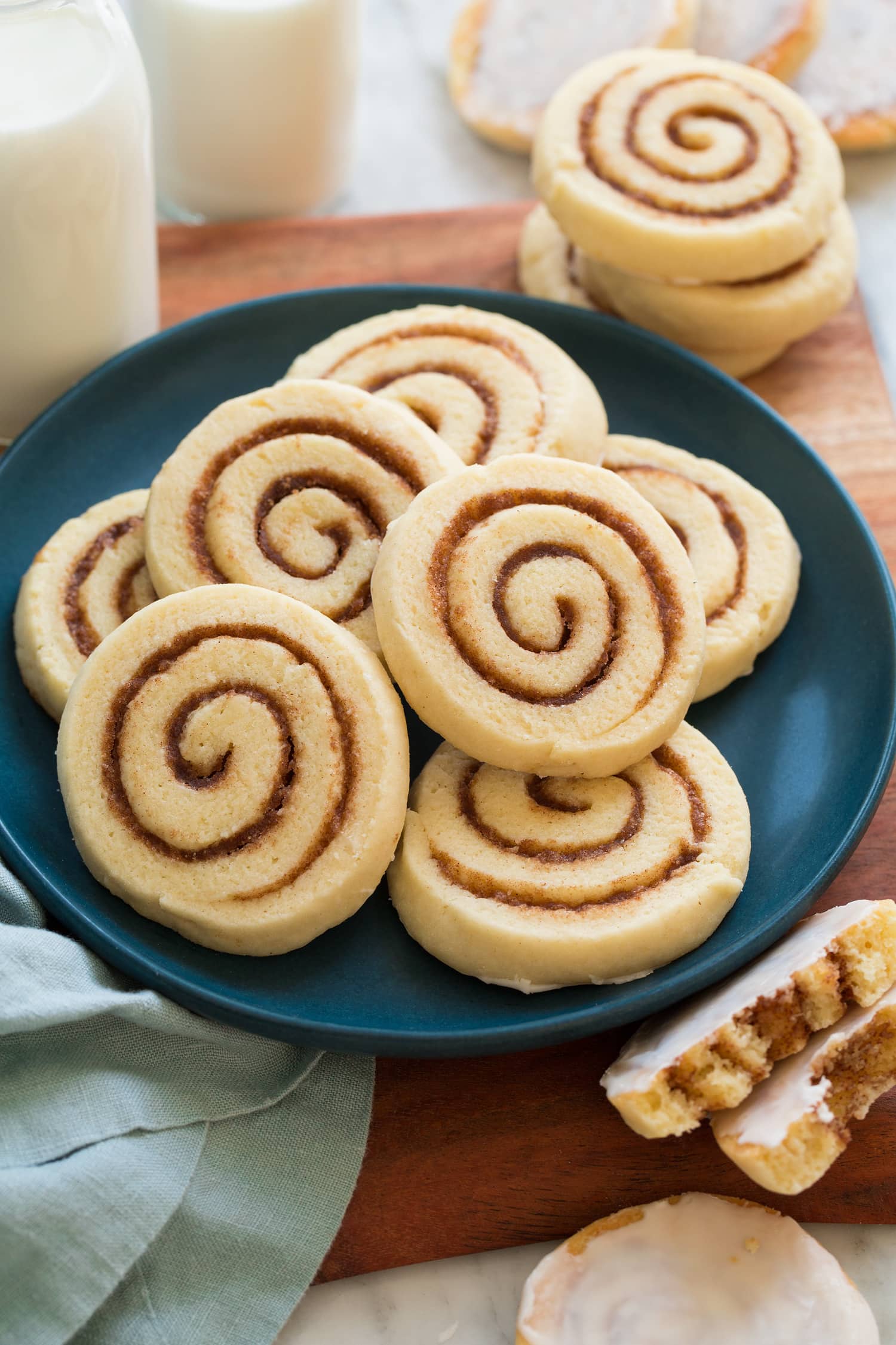 Cinnamon Roll Cookies Cinnamon roll cookies piled on a blue plate on a wooden surface.
