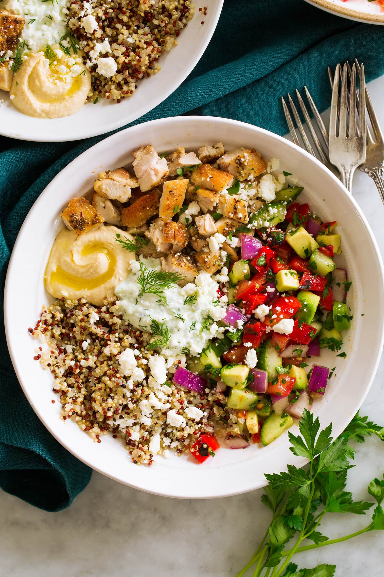 Greek Bowls Overhead photo of Greek chicken bowls with diced chicken thighs, greek salad, quinoa, hummus and tzatziki.