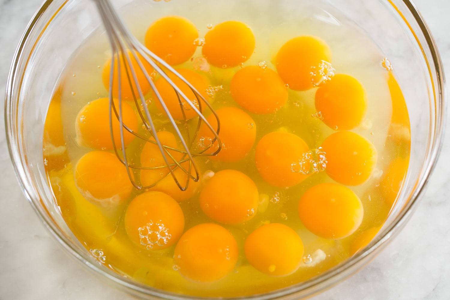 Sheet Pan Eggs 18 eggs in a glass mixing bowl being whisked together.