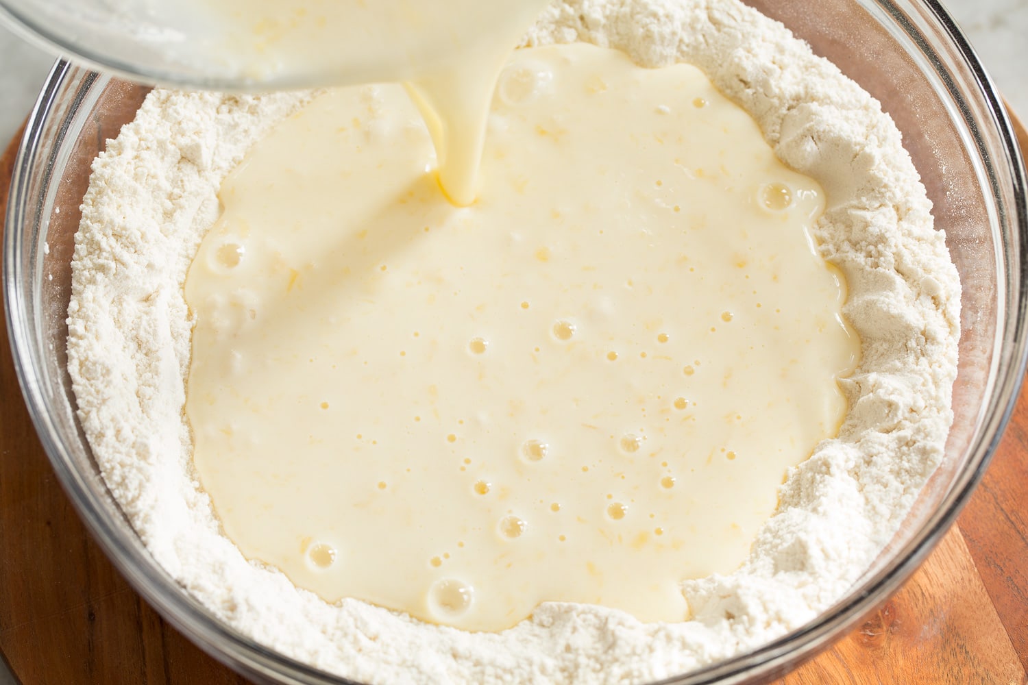 Sheet Pan Pancakes Pouring wet mixture into dry mixture for homemade pancake mix.