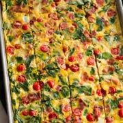 Bacon, tomato, spinach eggs in a baking sheet.