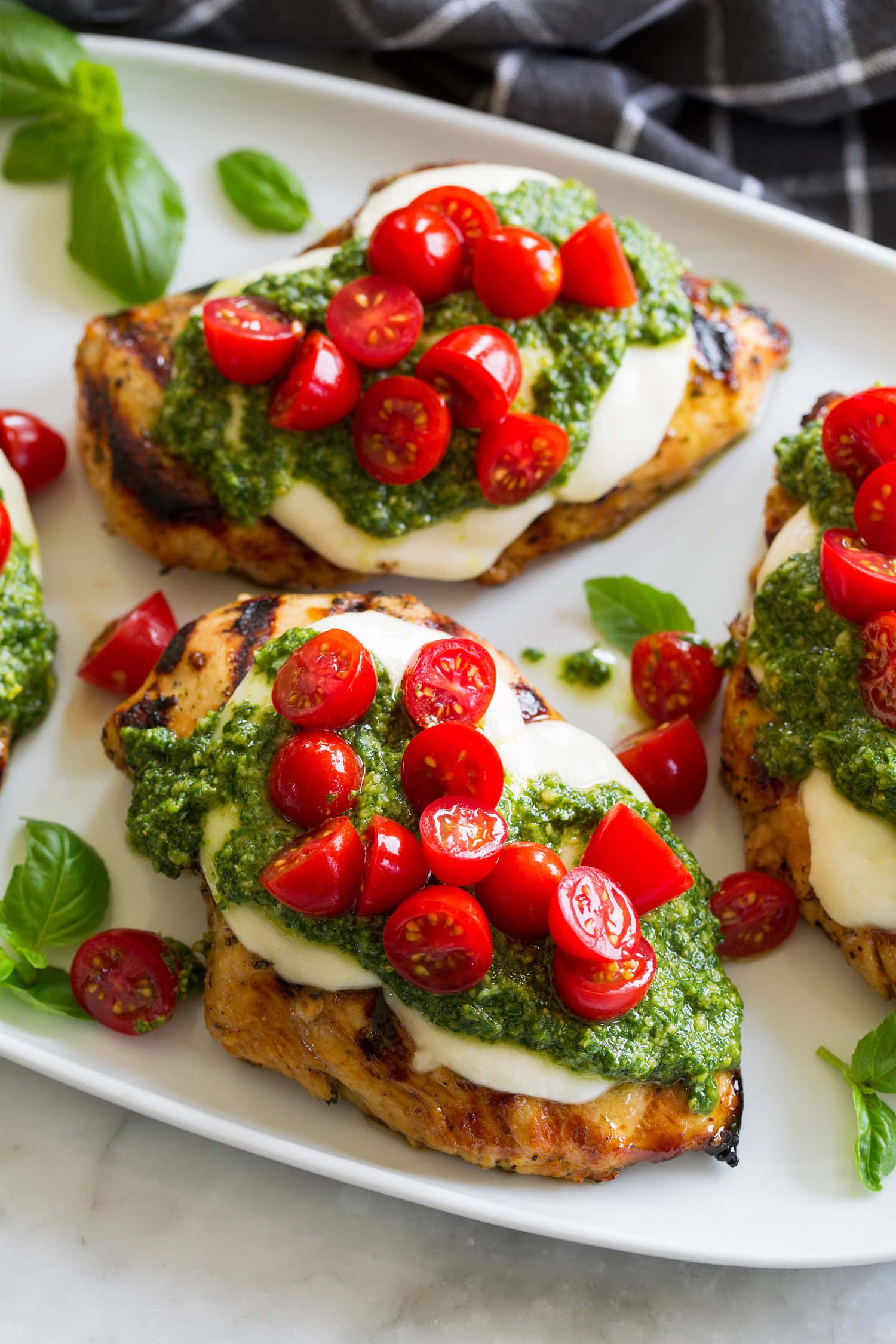 Grilled chicken margherita made with grilled chicken breasts, homemade pesto, fresh mozzarella and grape tomatoes.