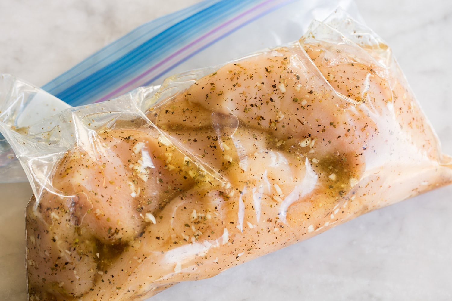 Grilled Chicken Margherita Chicken soaking in marinade in ziplock bag.