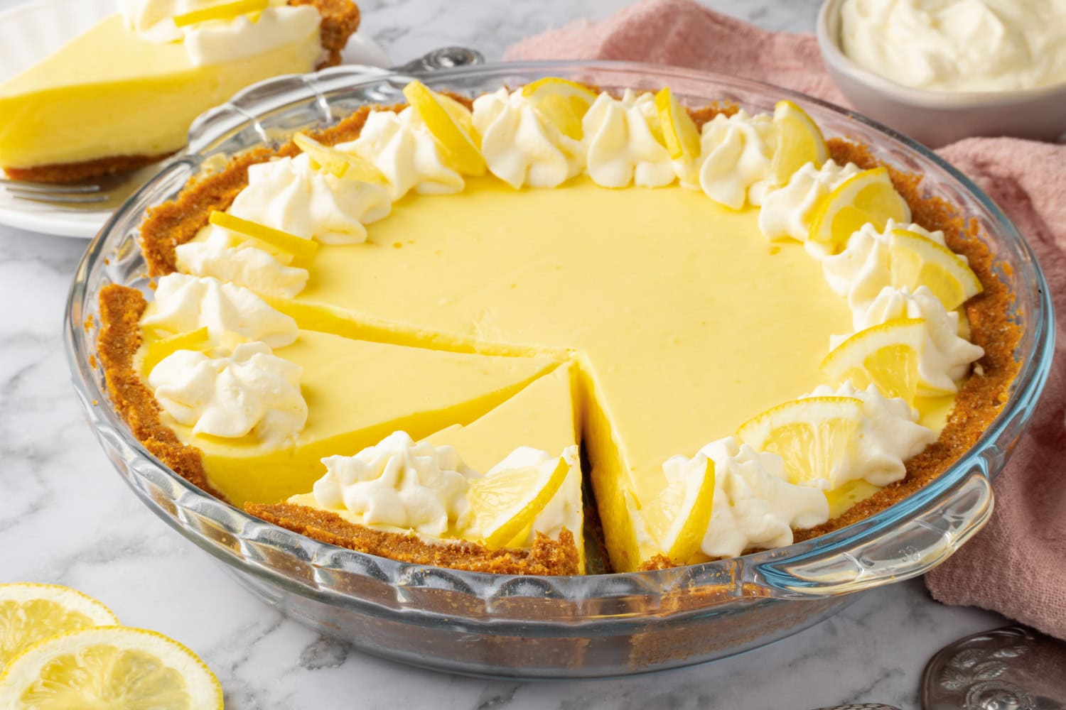 It's garnished with whipped cream swirls and lemon slices. Lemon pie slice and shown from the side.