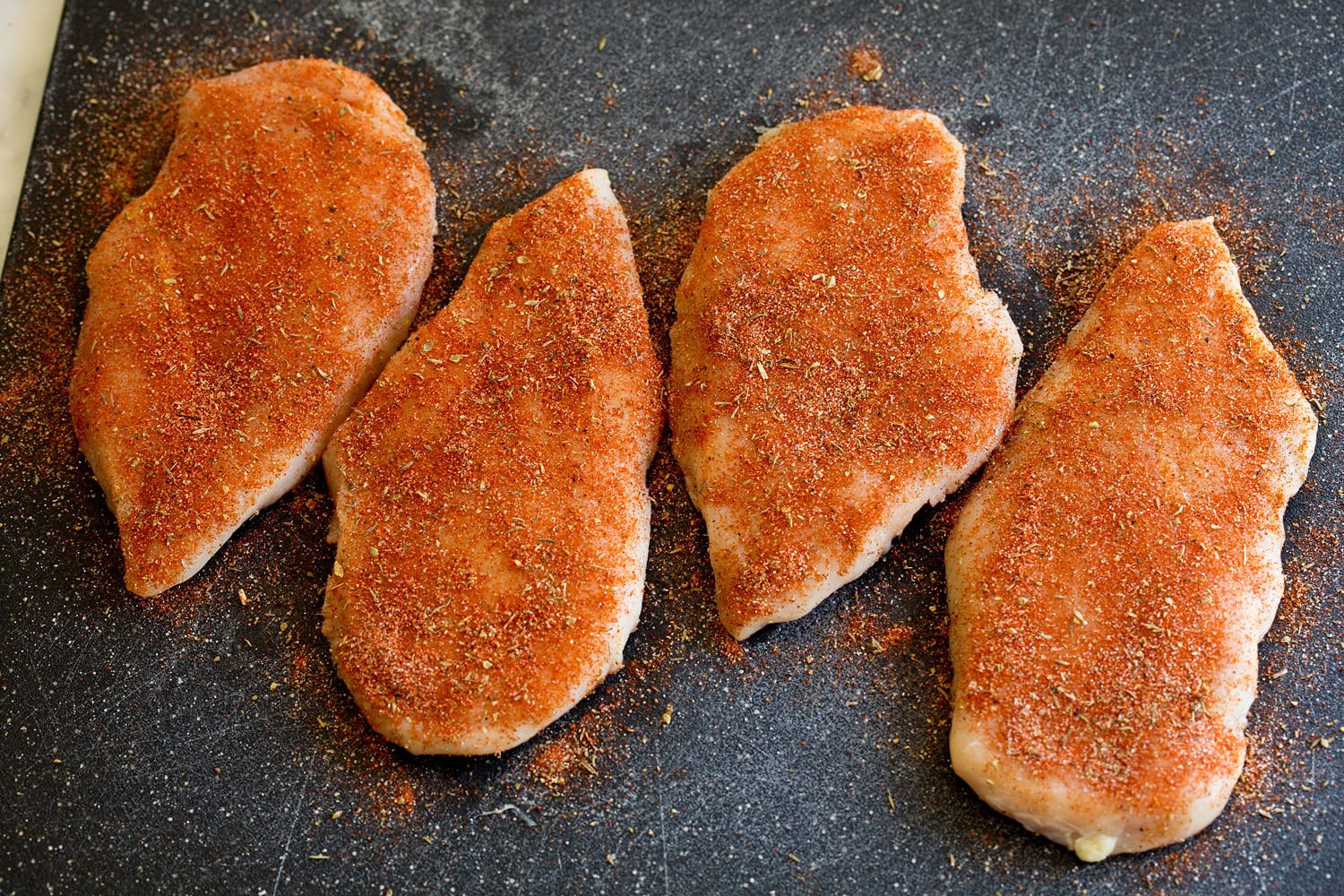 Blackened Chicken Breasts Spice seasoned chicken breasts shown before cooking.