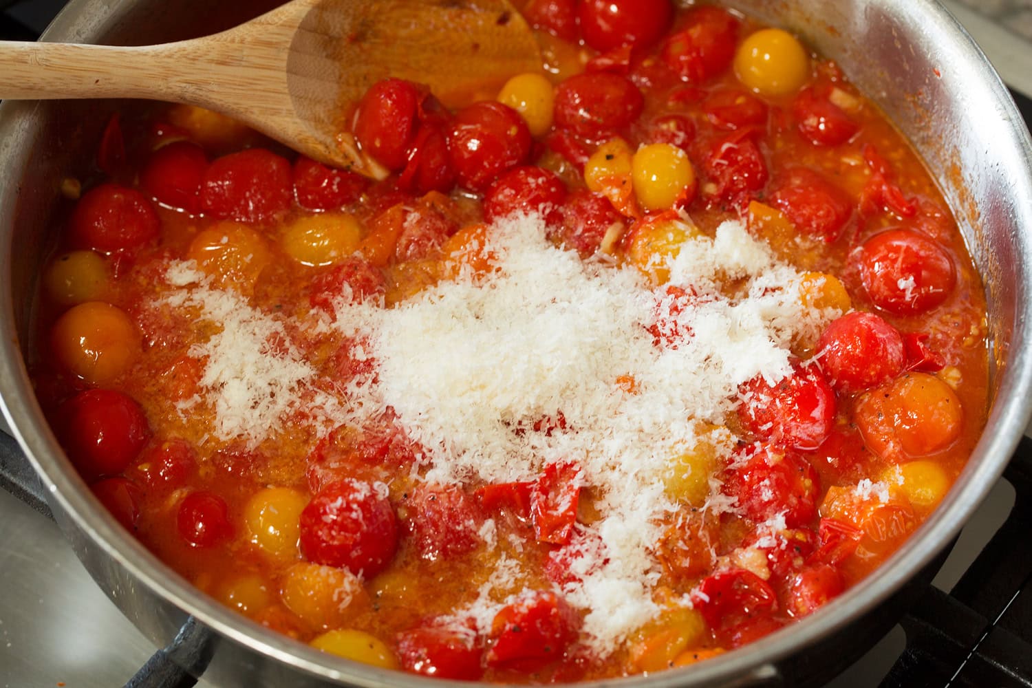 Burst cherry tomato sauce with parmesan being added. Burst cherry tomato sauce with parmesan being added.