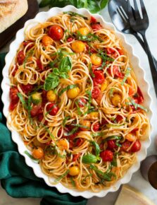 Cherry tomato pasta on a white oval scalloped serving platter.
