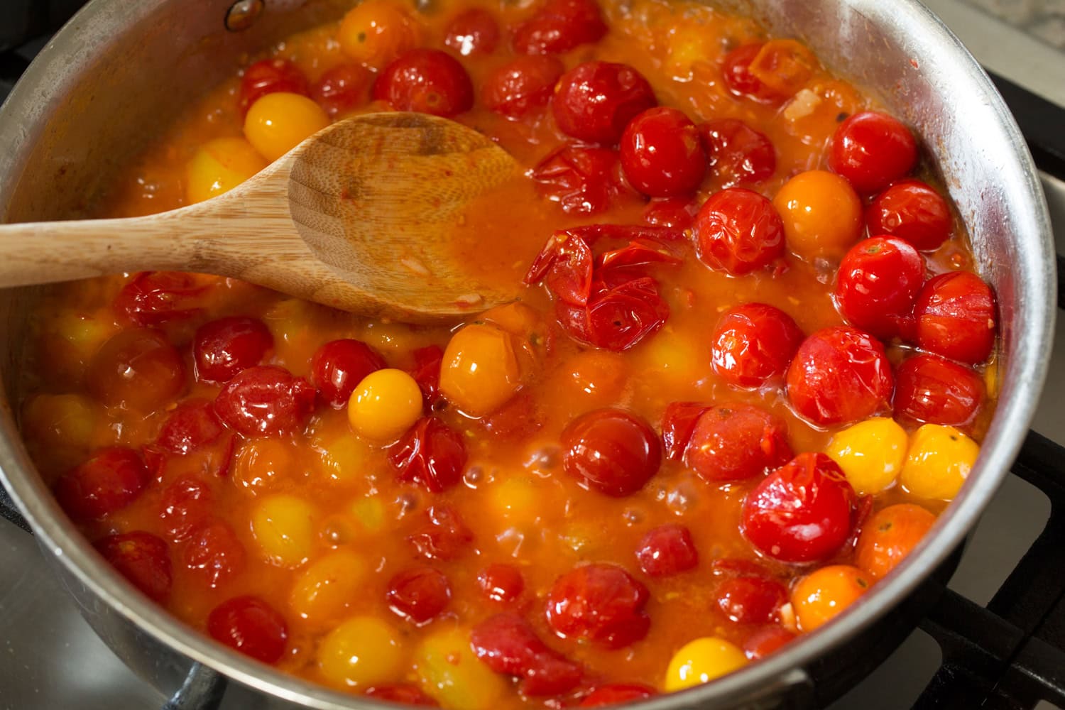 Cherry Tomato Sauce Smashing cherry tomatoes into sauce in saute pan.