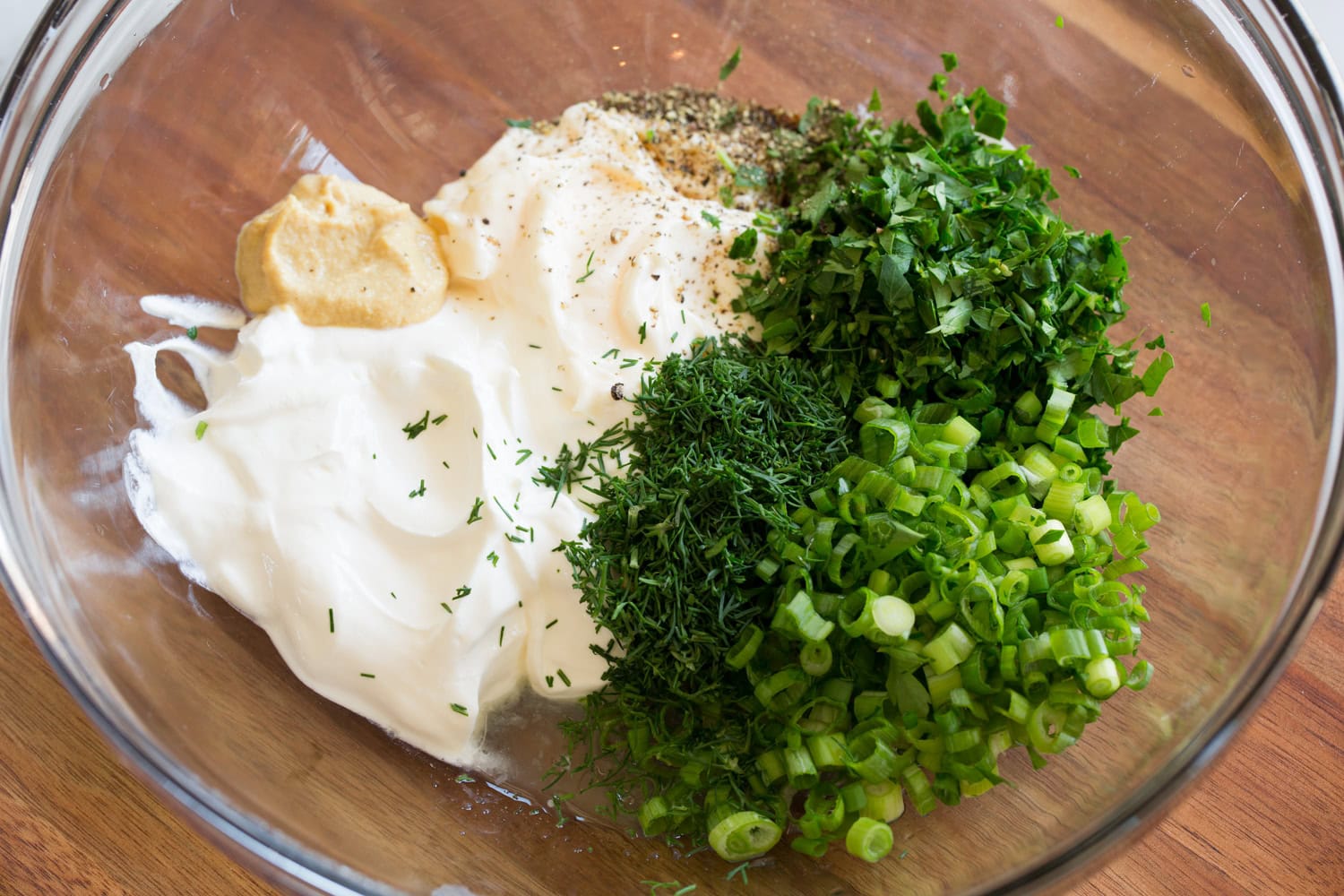 Red Potato Salad Mayonnaise, sour cream mustard and herbs in a mixing bowl shown before blending.
