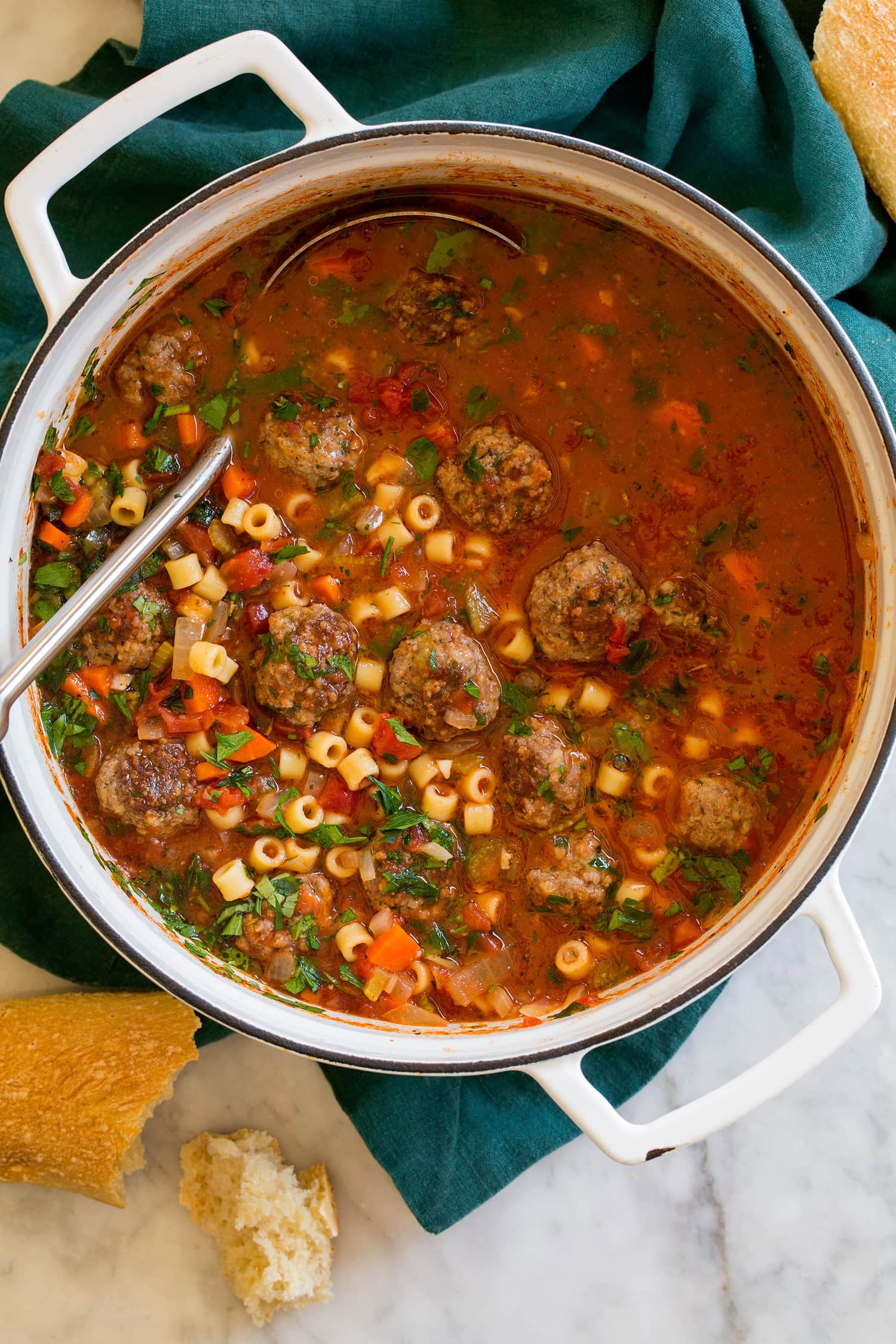 Meatball Soup Overhead photo of meatball soup in a white pot over a blue cloth.