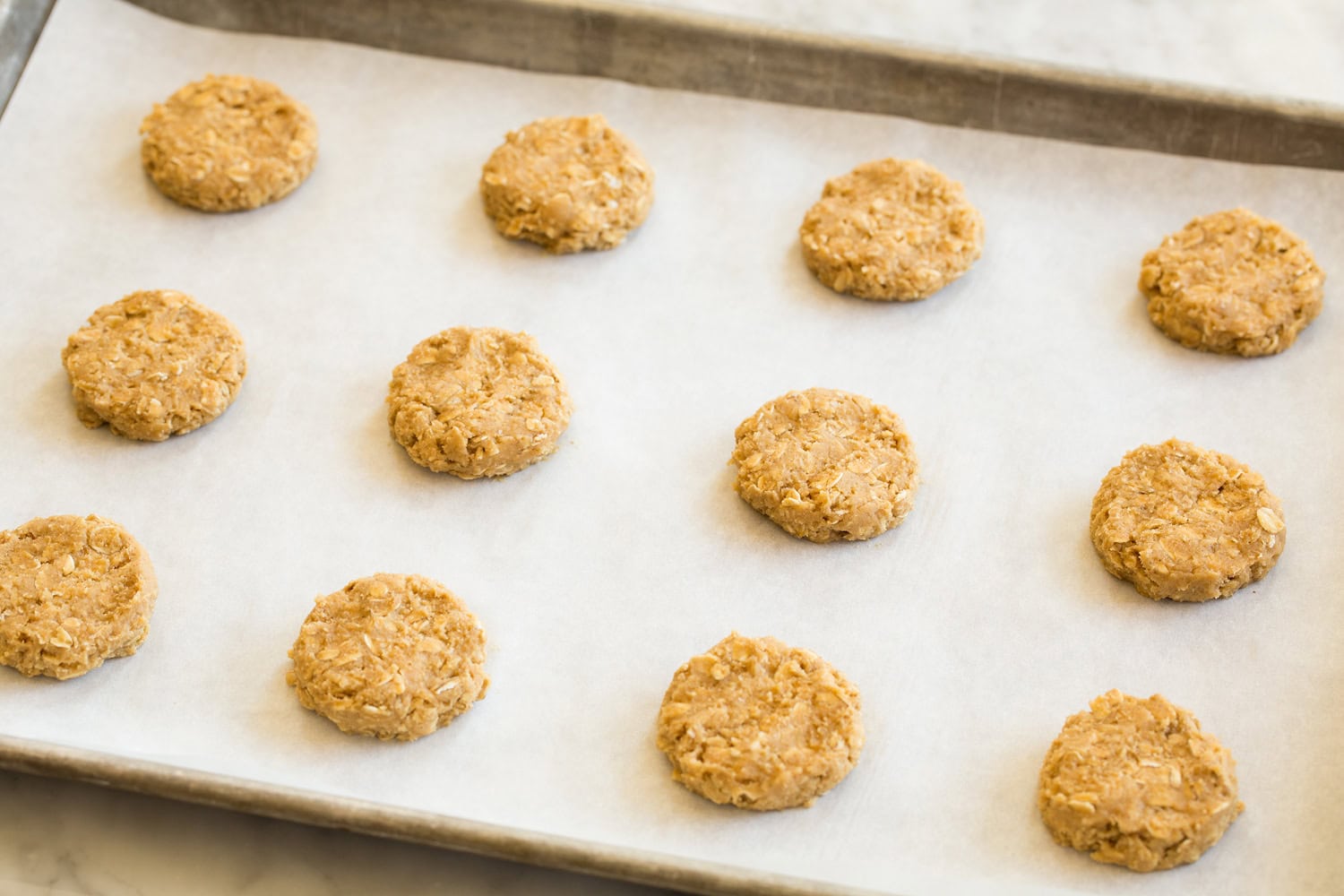 Oatmeal Cream Pies Oatmeal cookies shown before baking on parchment lined baking sheet.