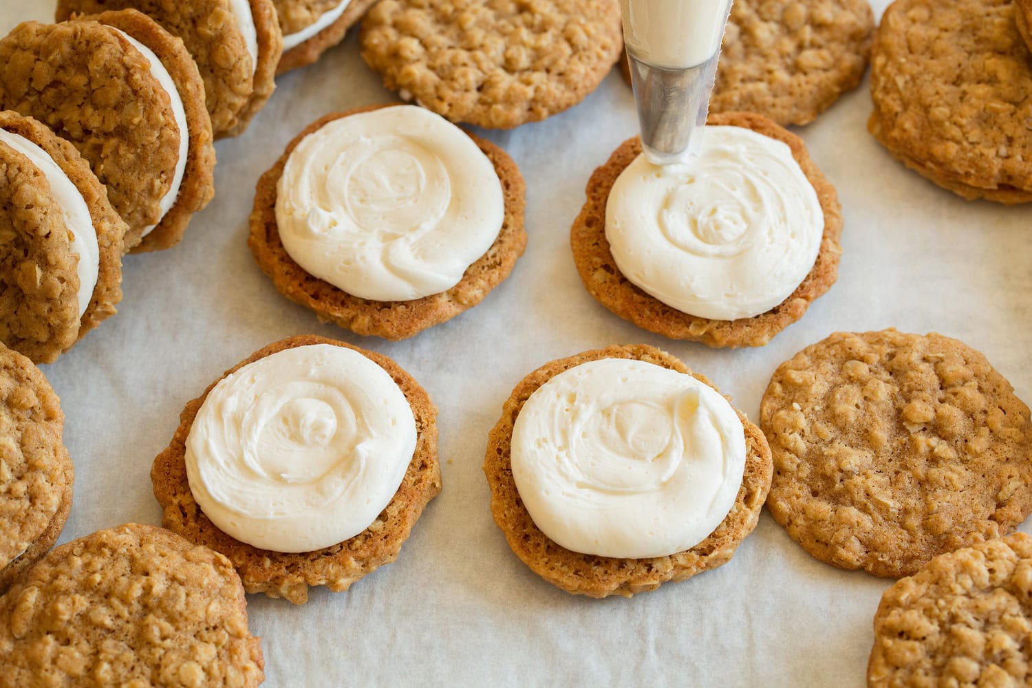 Oatmeal Cream Pies Oatmeal cookies being topped with cream pie frosting filling.