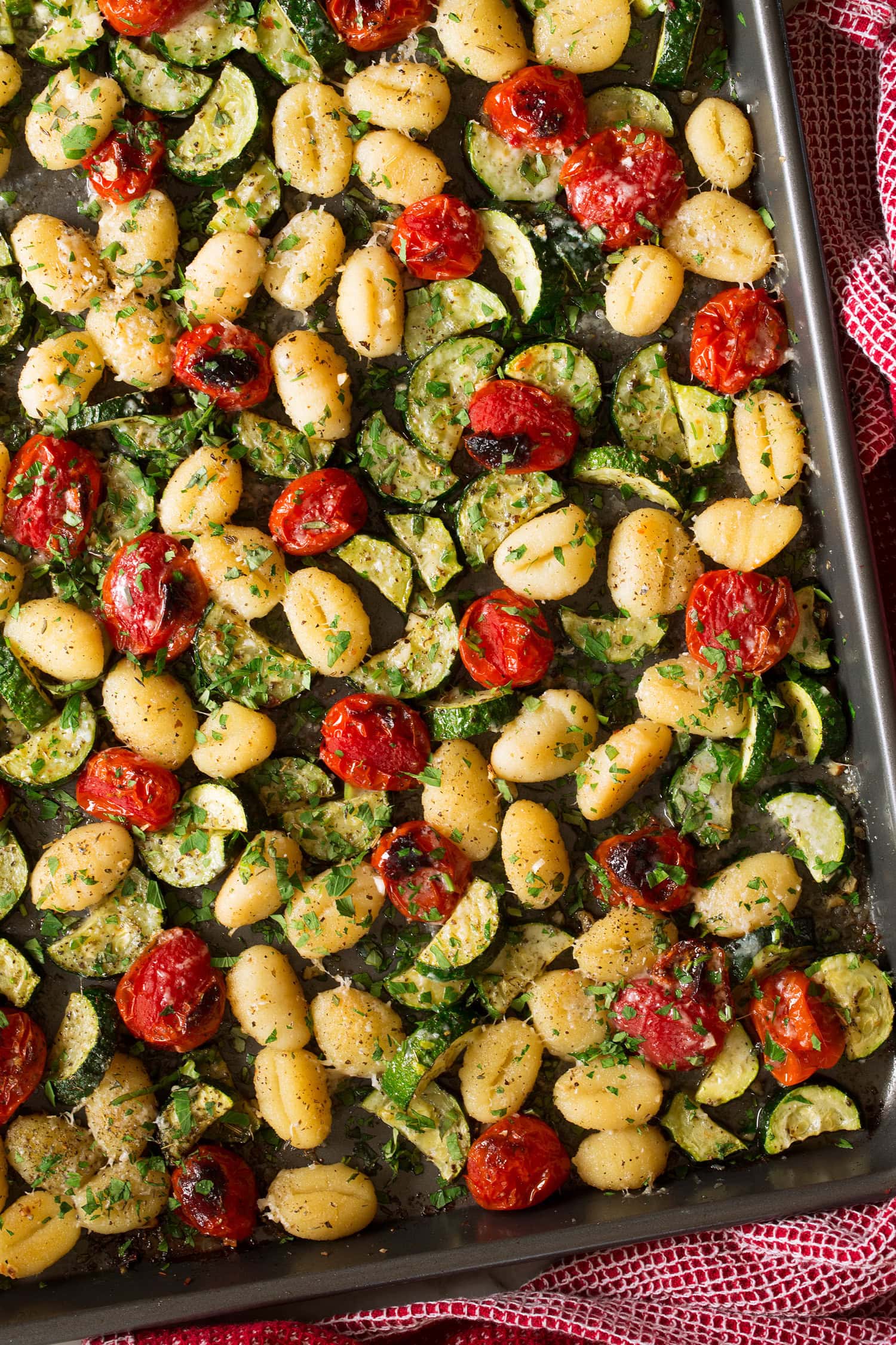 Sheet Pan Gnocchi with Zucchini and Tomatoes Close up photo of gnocchi on sheet pan with tomatoes and zucchini.