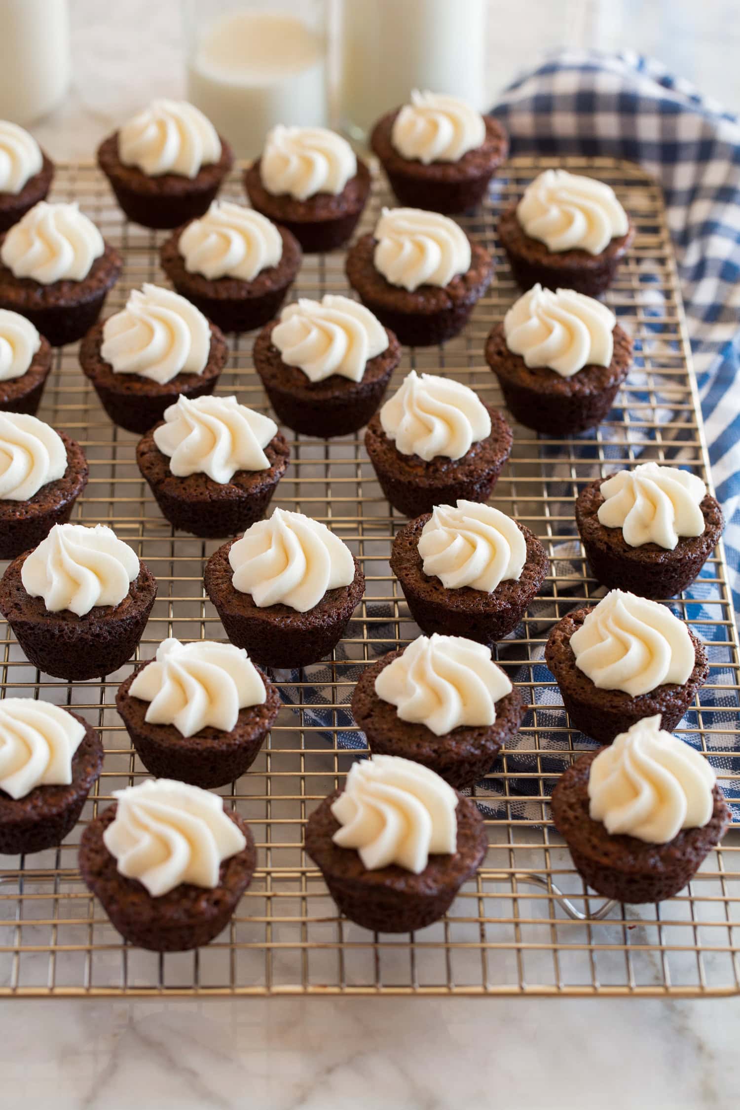 Brownie Bites Cream cheese frosting topped brownie bites on a wire cooling rack.