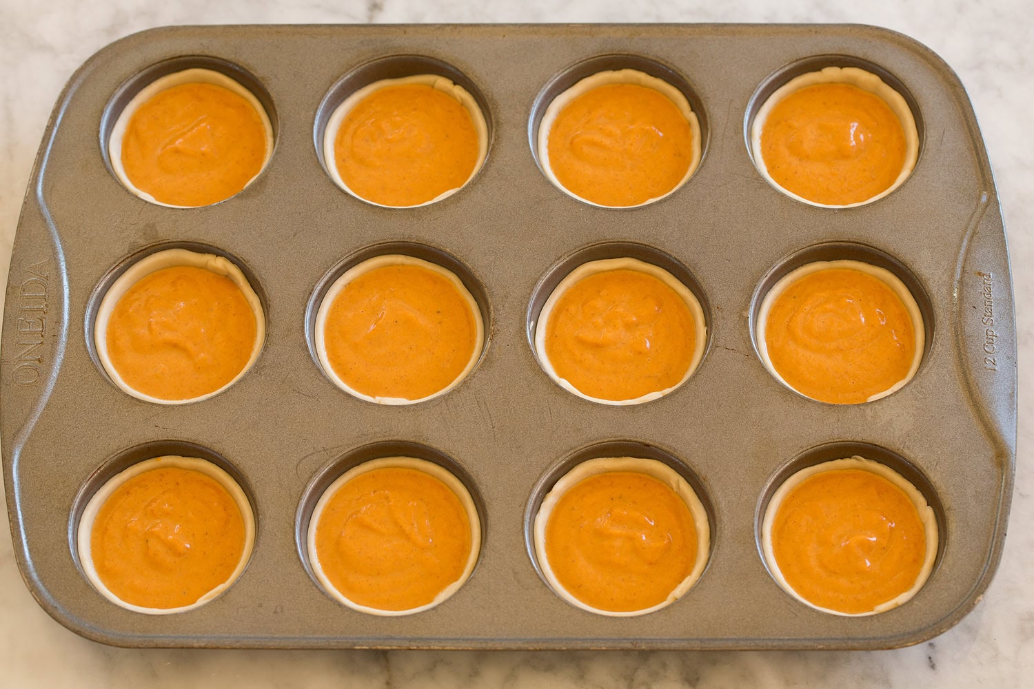 Mini Pumpkin Pies Pumpkin pie filling poured into mini pie crusts in muffin pan.