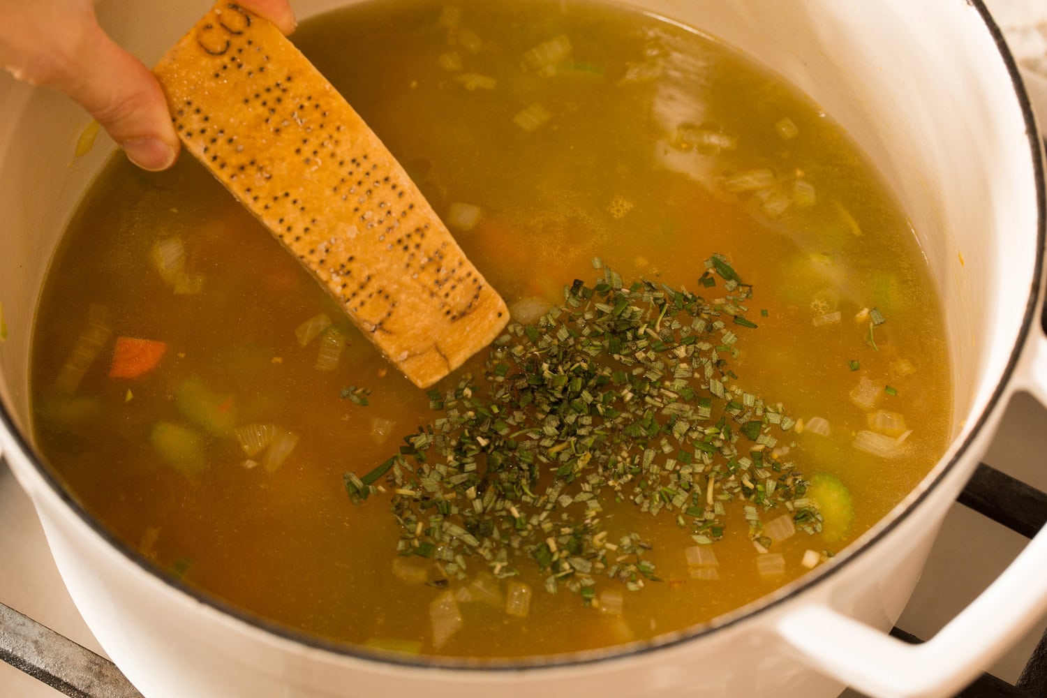 White Bean and Kale Soup Broth, parmesan rind and herbs added to pot.