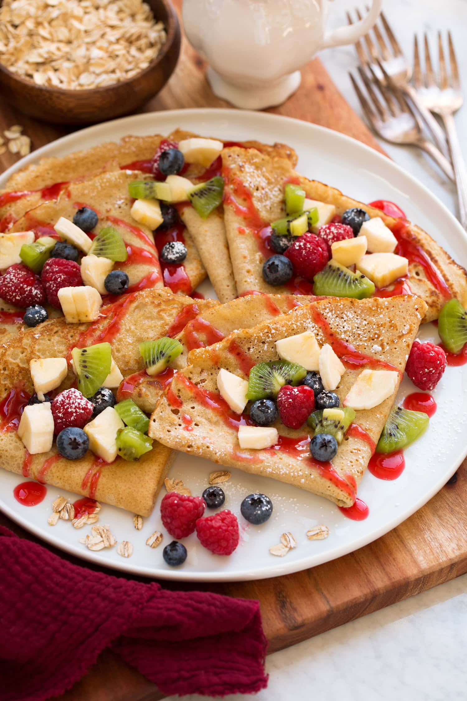 Healthy Oat Crepes Oatmeal crepes shown folded with fresh fruit and berry syrup drizzled over the top.