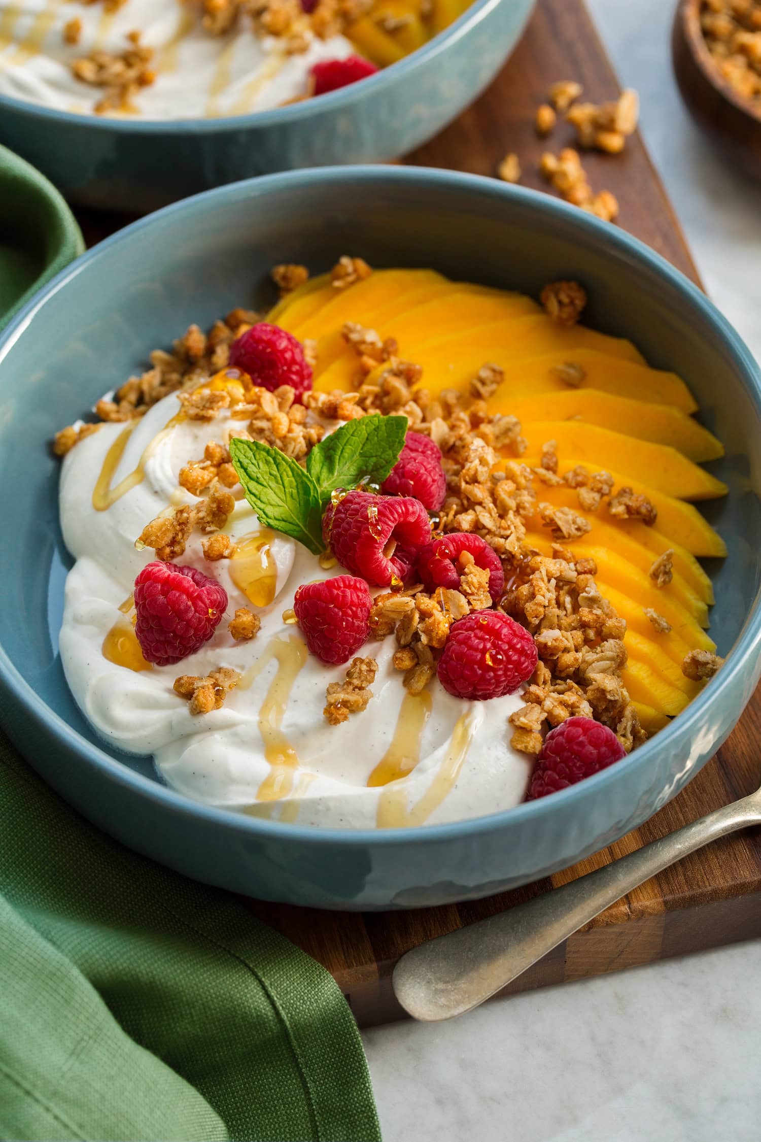 Whipped yogurt shown with honey drizzled over, fruit and granola on the side.