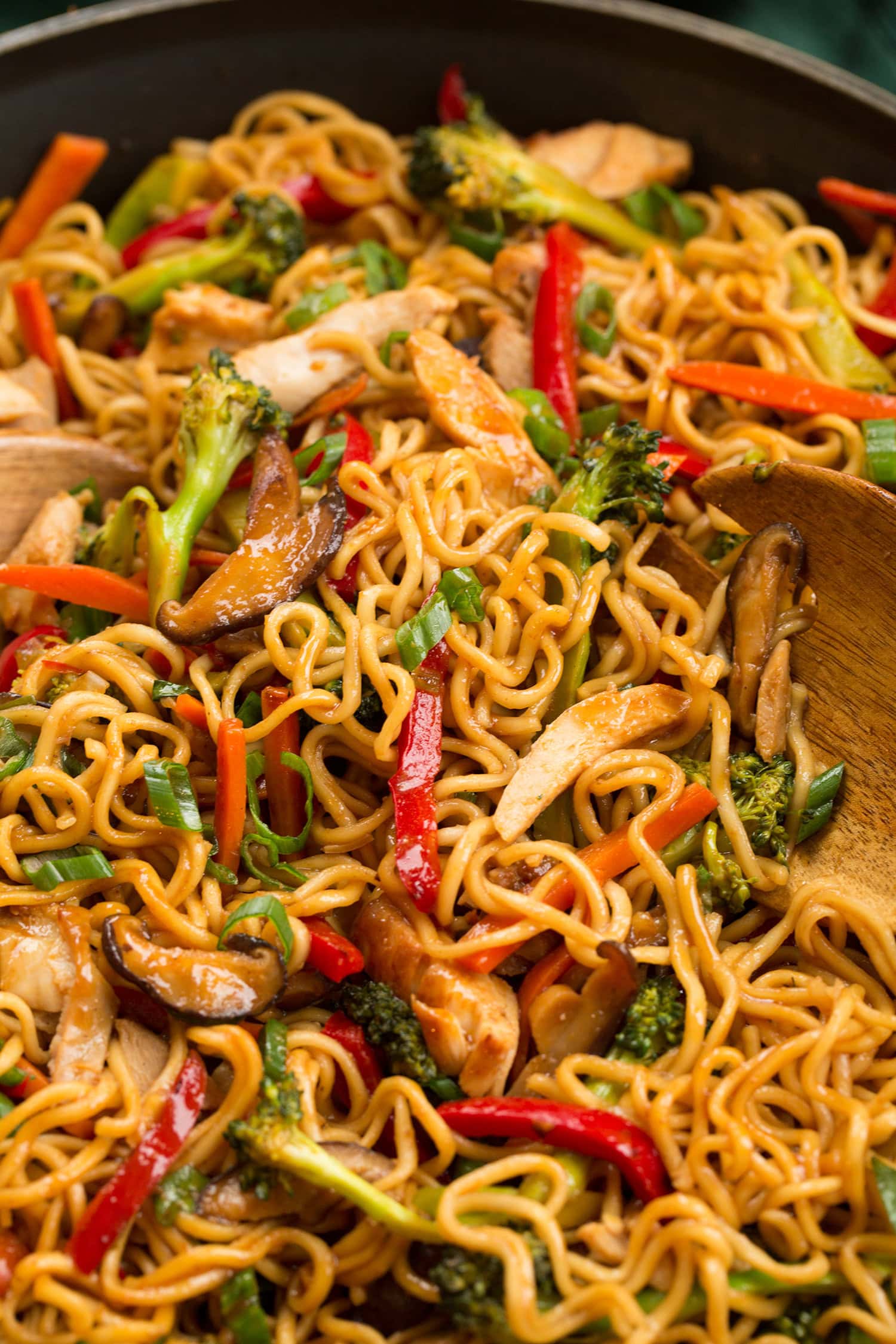 Stir fry noodles with chicken and vegetables shown close up in a skillet.
