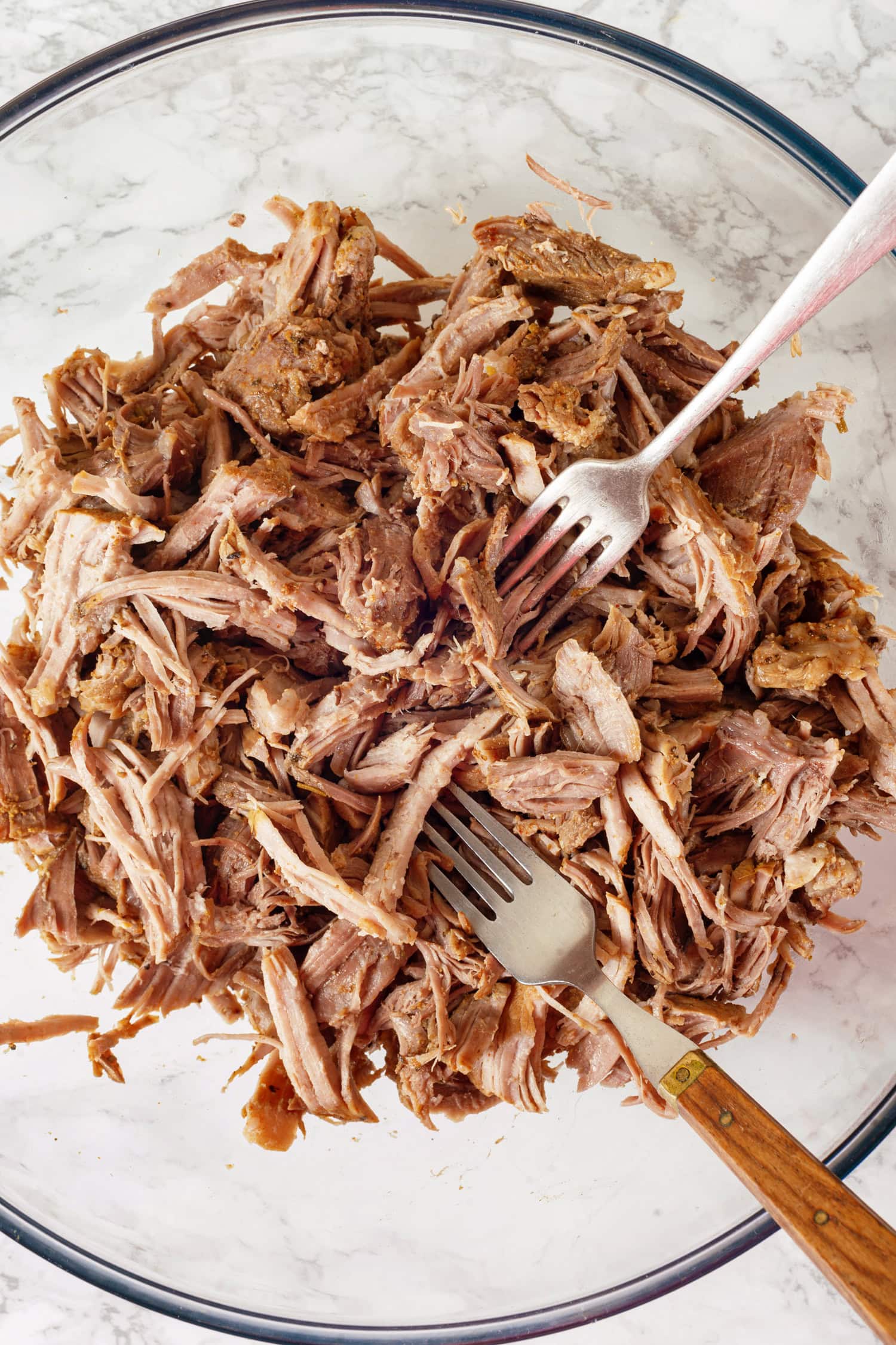 Shredding cooked pork in a bowl.